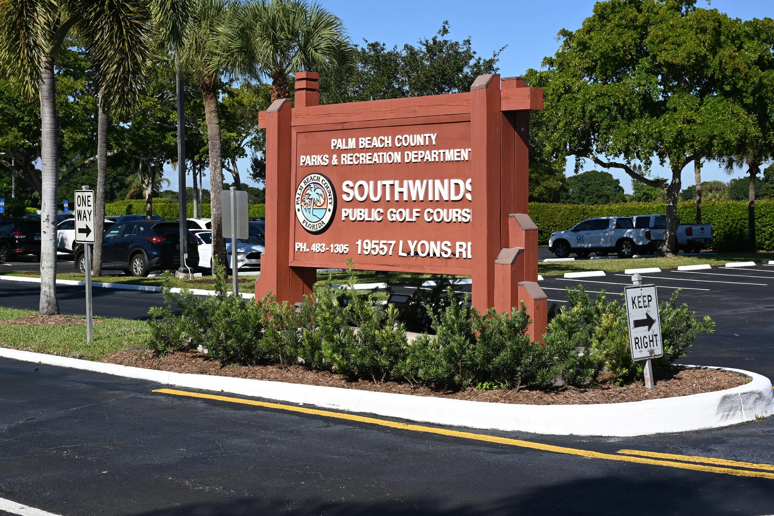 Sign for Palm Beach County Parks & Recreation Department and Southwinds Public Golf Course, located at 19557 Lyons Road in Florida, with parking lot and trees in the background.
