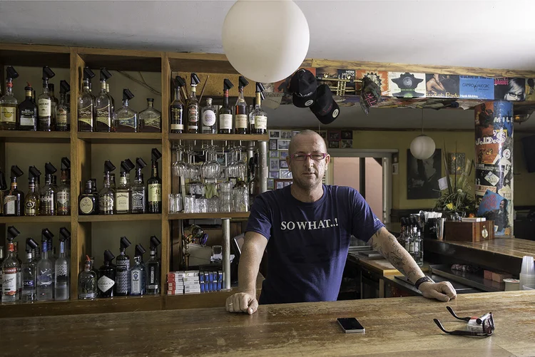Bartender standing behind a fully stocked bar at a Curaçao cafe