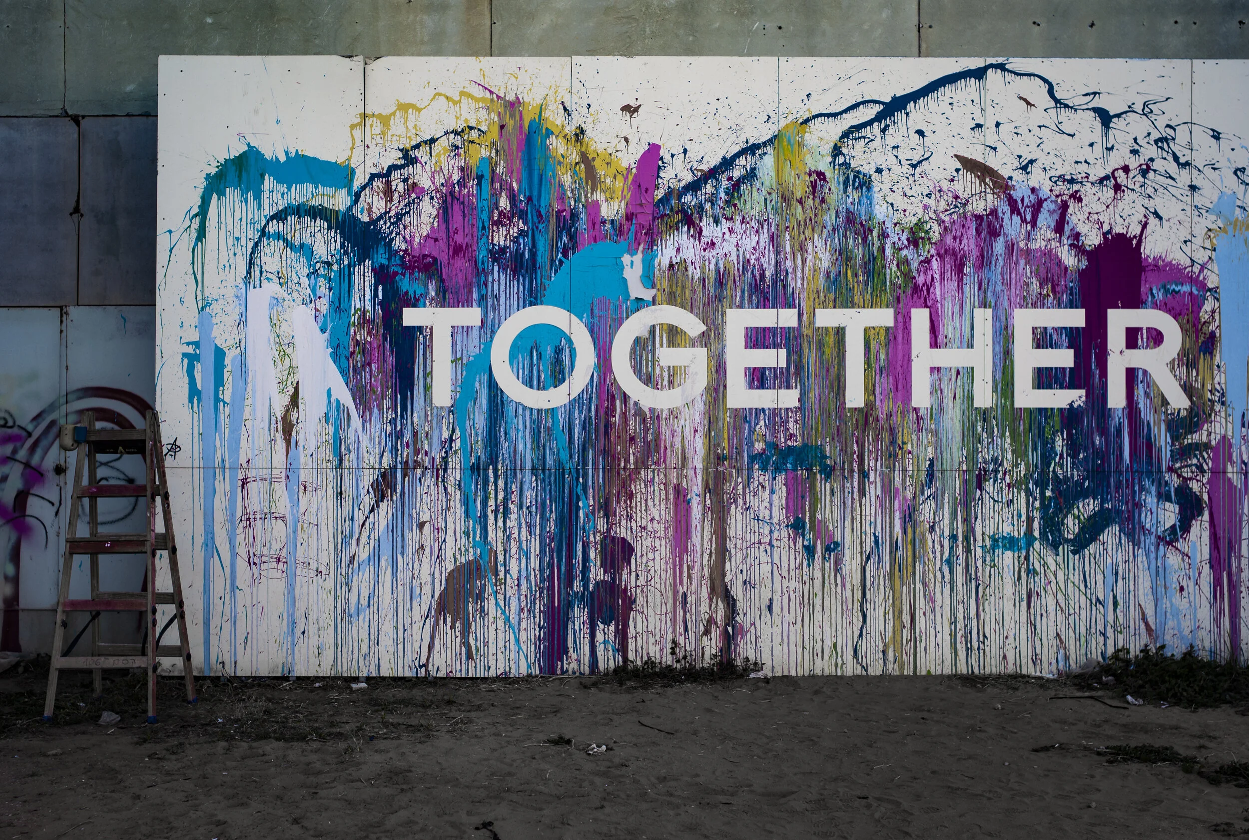 Wall with colourful painting spilled over forming the word Together