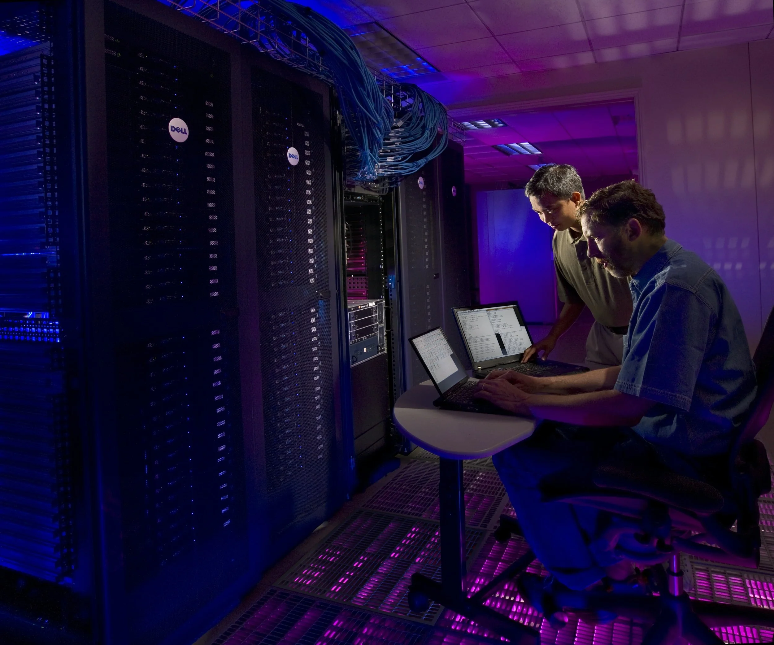 2 engineers coding in a server room