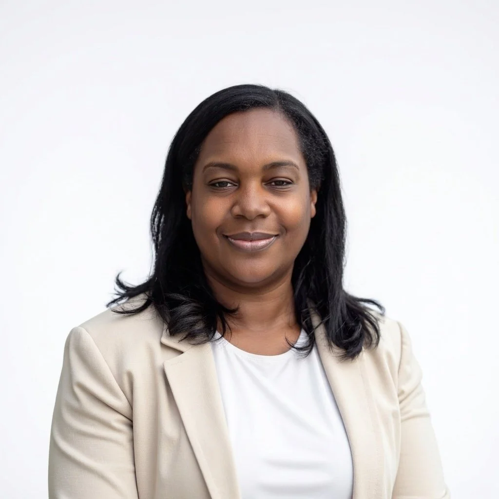 A woman with medium skin tone and shoulder-length black hair, wearing a beige blazer and white top, smiling slightly against a plain white background.