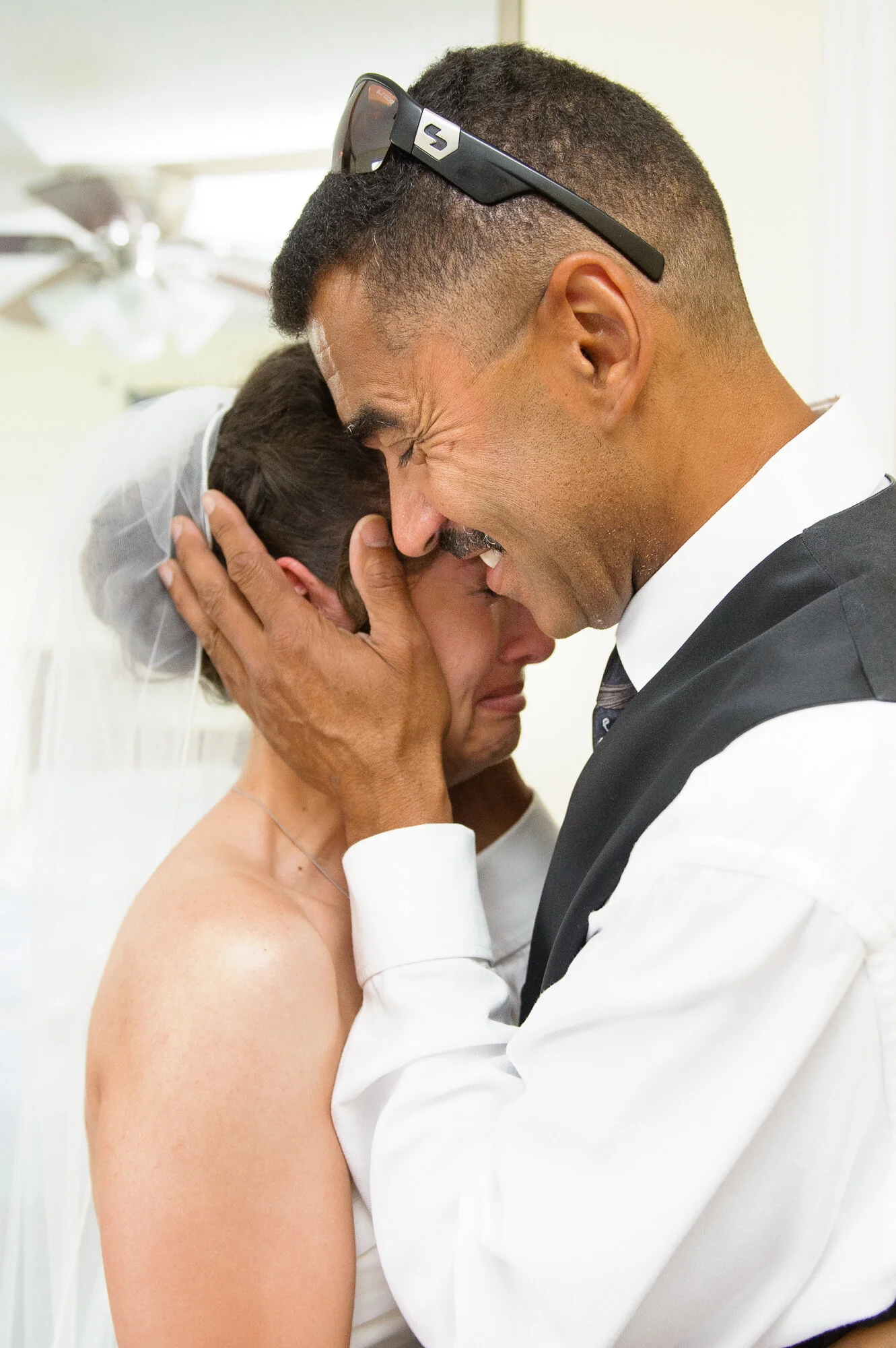 Emotional embrace between a bride and man in formal attire