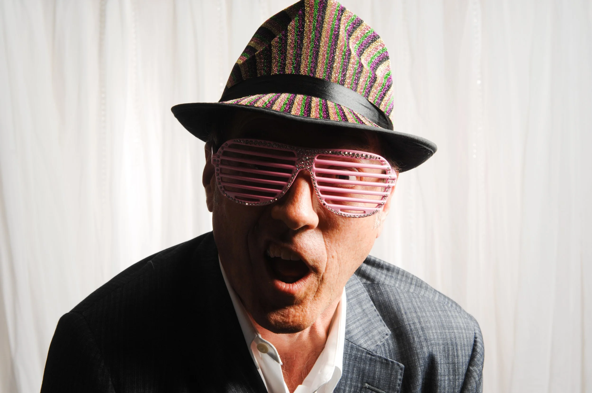 Man wearing a colorful hat and pink shutter shades