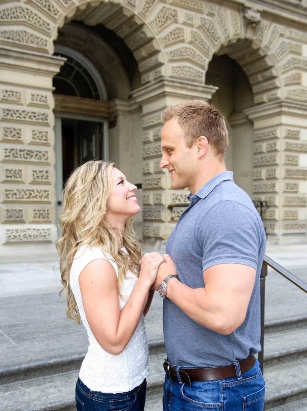 Engagement Photography of young Couple in front of  U of T . Holding hands and gazing at each other with joyful expressions.