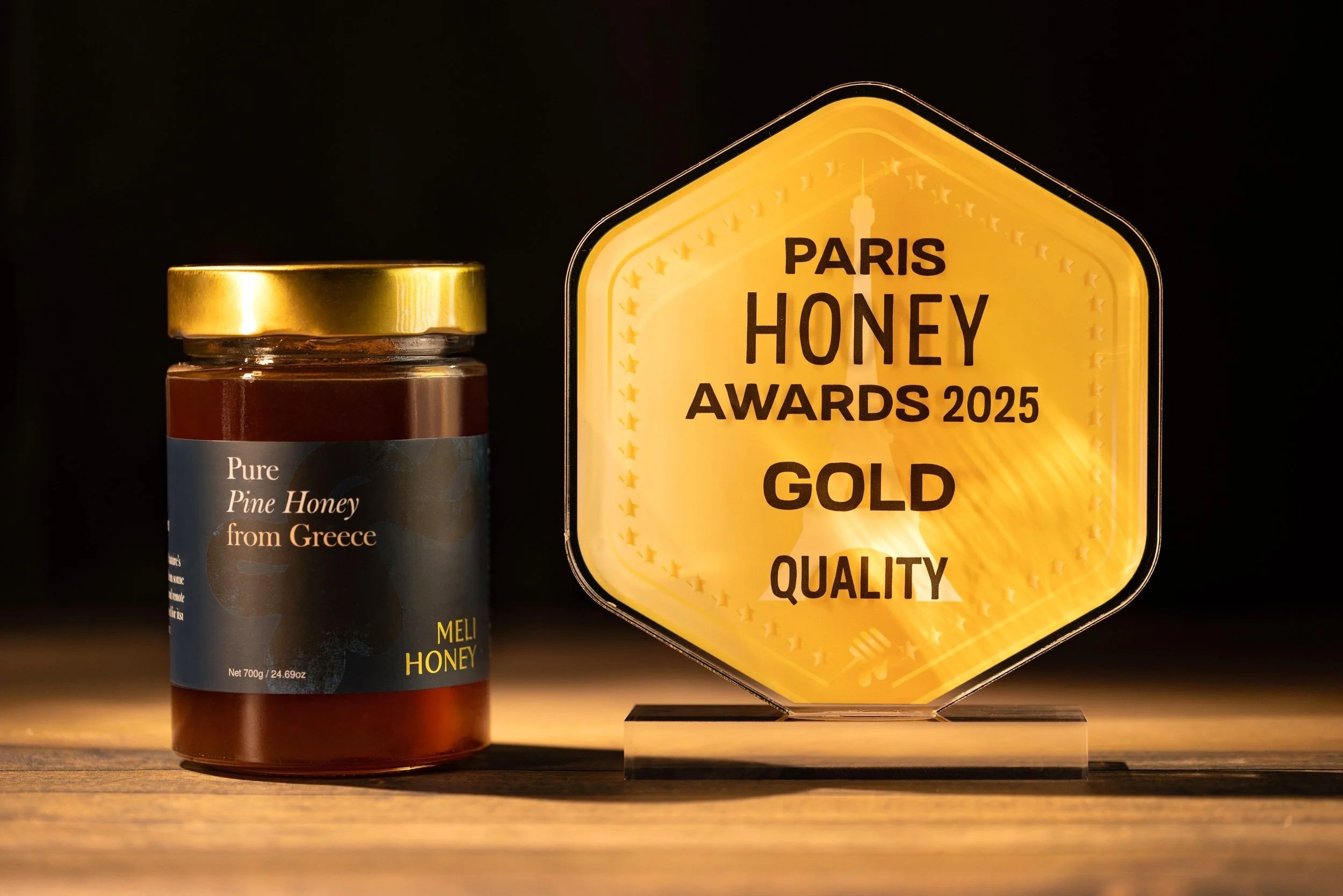 A jar of pure pine honey from Greece next to a 2025 Paris Honey Awards gold medal.
