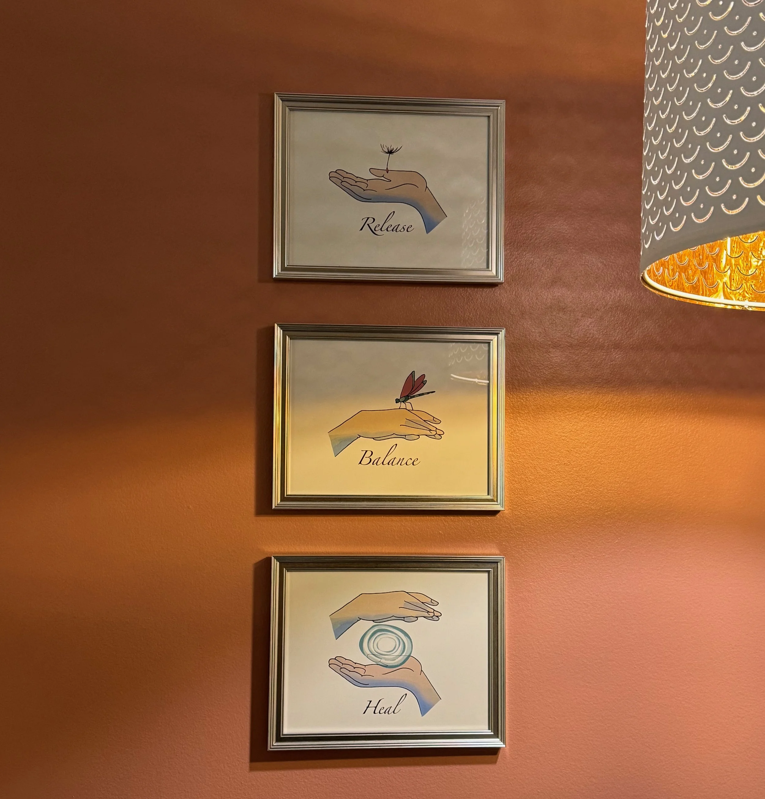 3 framed graphics of hands, one releasing a dandelion puff, another with a dragonfly balancing on it and last two hands with an orb between them. the words Release, Balance, Heal are below each image.
