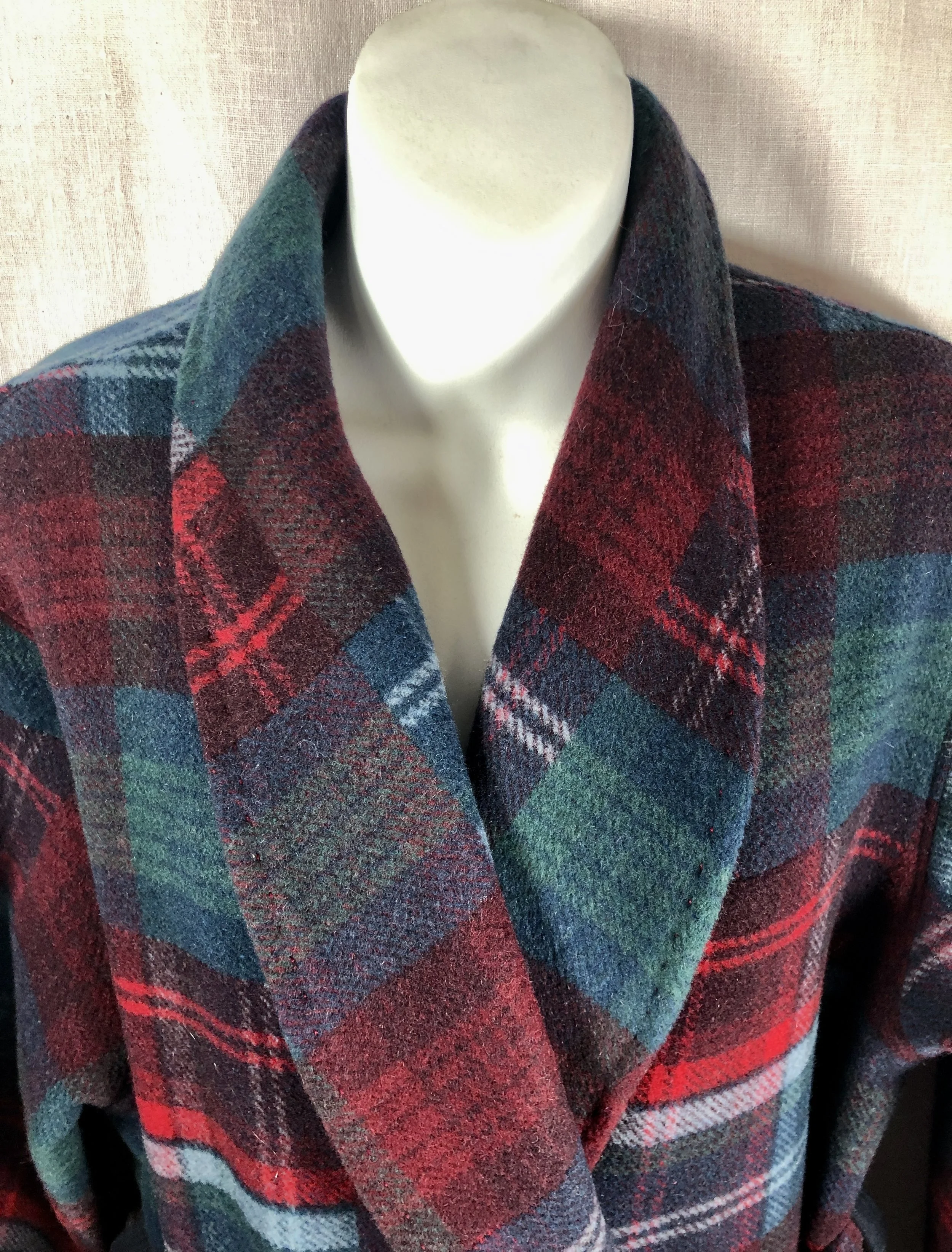 A mannequin wearing a multicolored, plaid wool bathrobe with a large collar, featuring red, green, blue, and black patterns.
