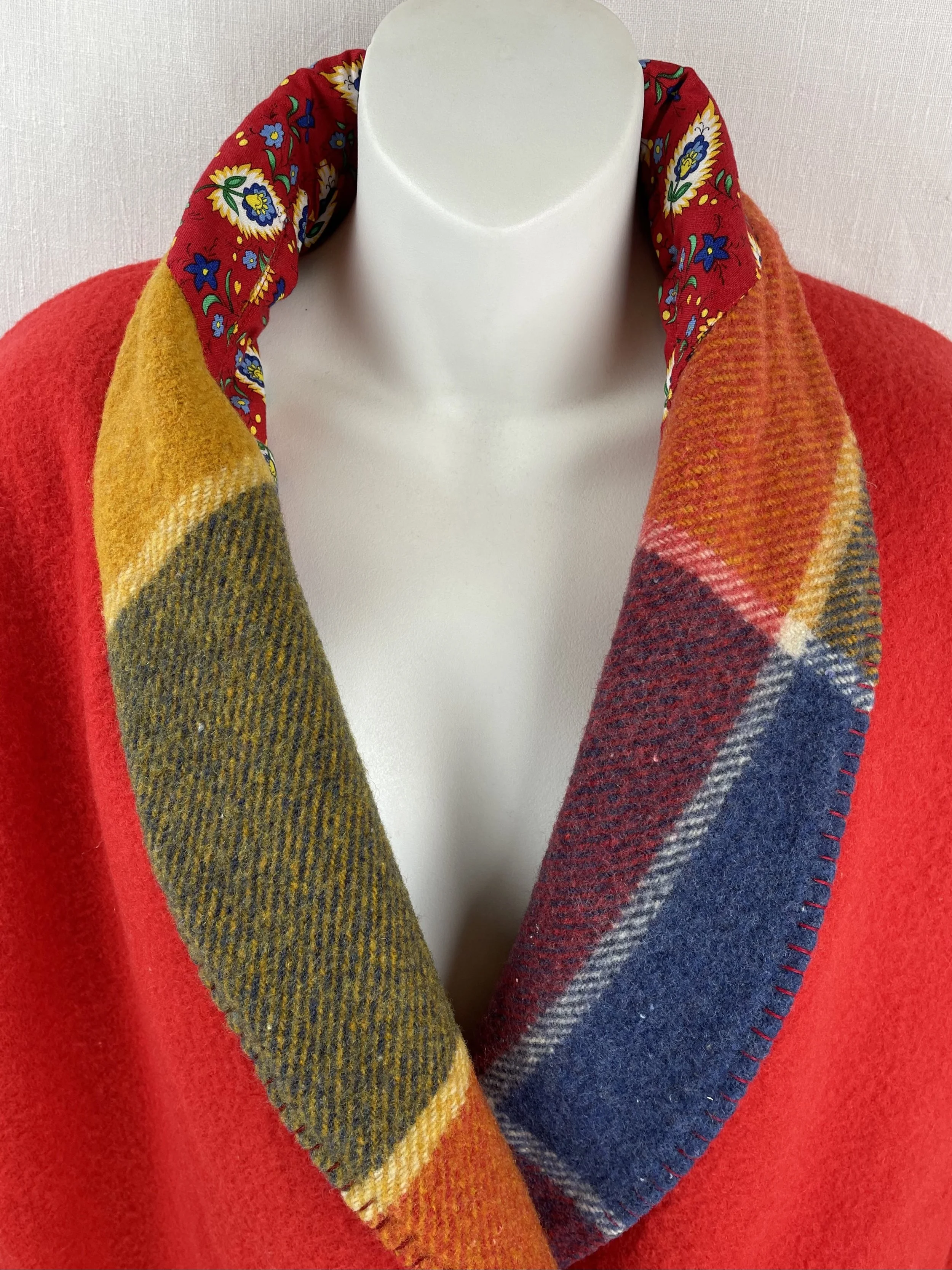 A mannequin with a red wool dressing robe with a multicolored collar, featuring a red background with floral pattern details along the scarf.