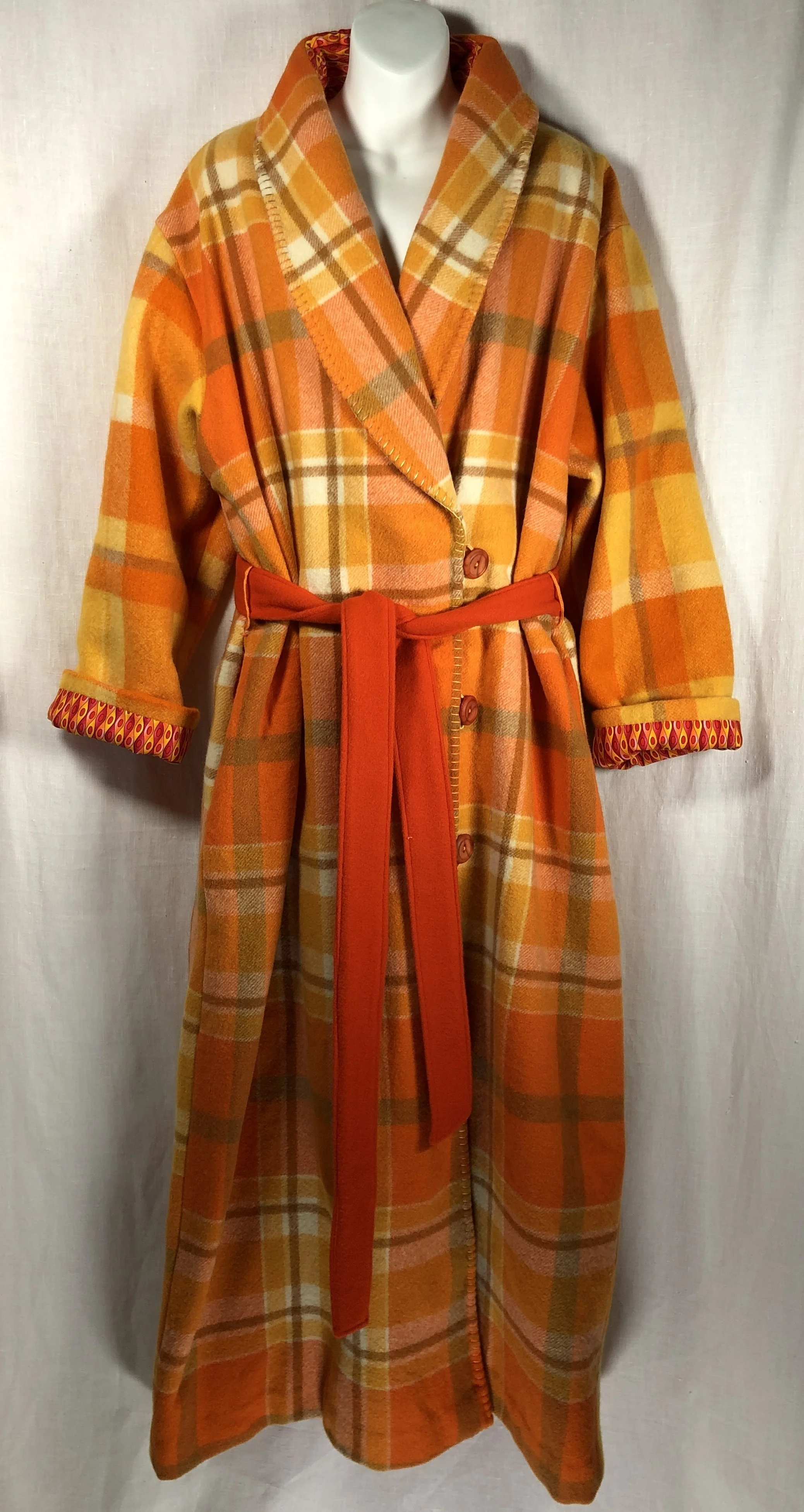 Long winter wool dressing gown with orange and yellow plaid pattern, red belt, and rolled-up sleeves showing a patterned lining.