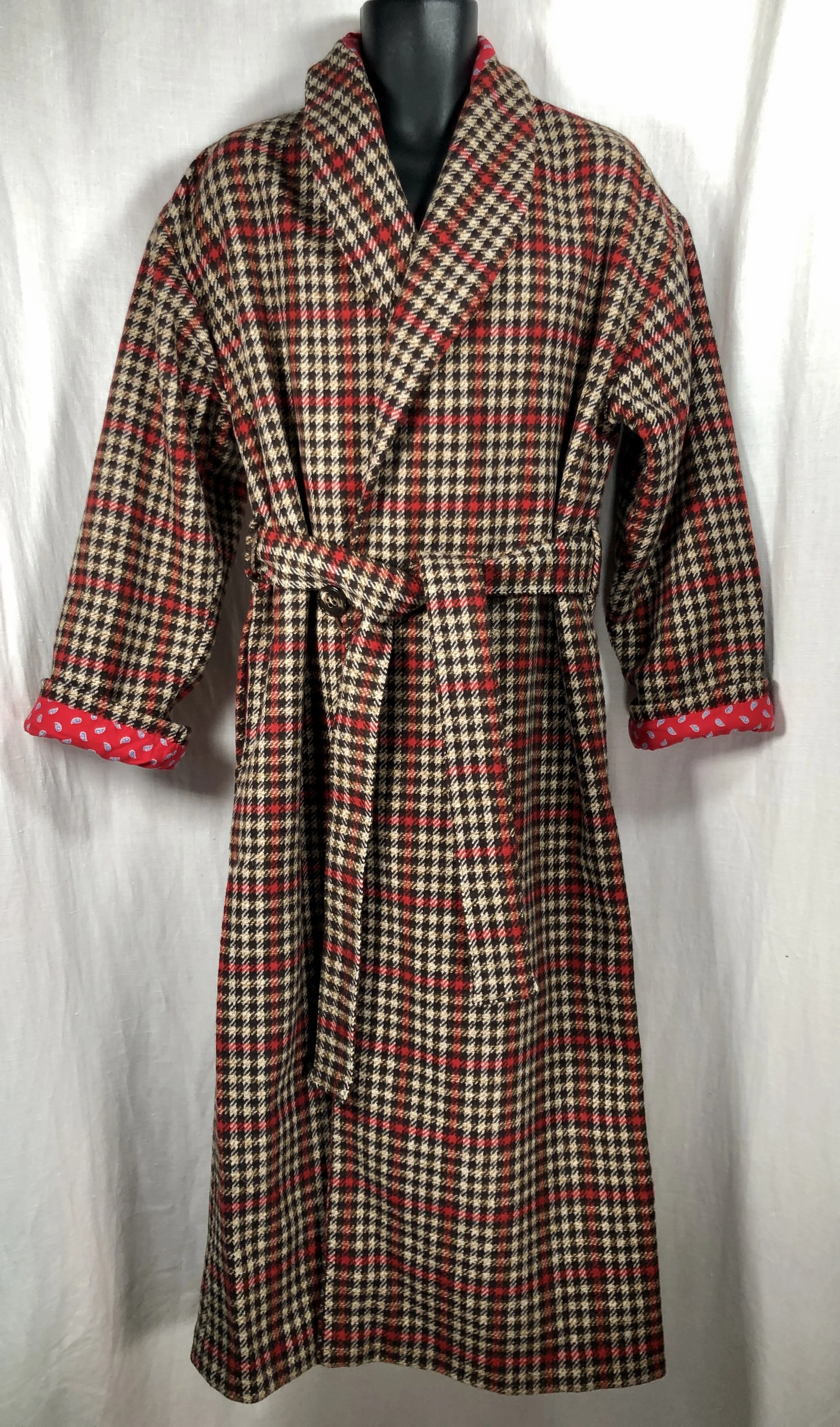 A long mens Italian wool dressing robe using coat fabric from 1940, featuring a belt at the waist, rolled-up sleeves with red polka-dotted lining, and a collar, displayed on a black mannequin against a white backdrop.