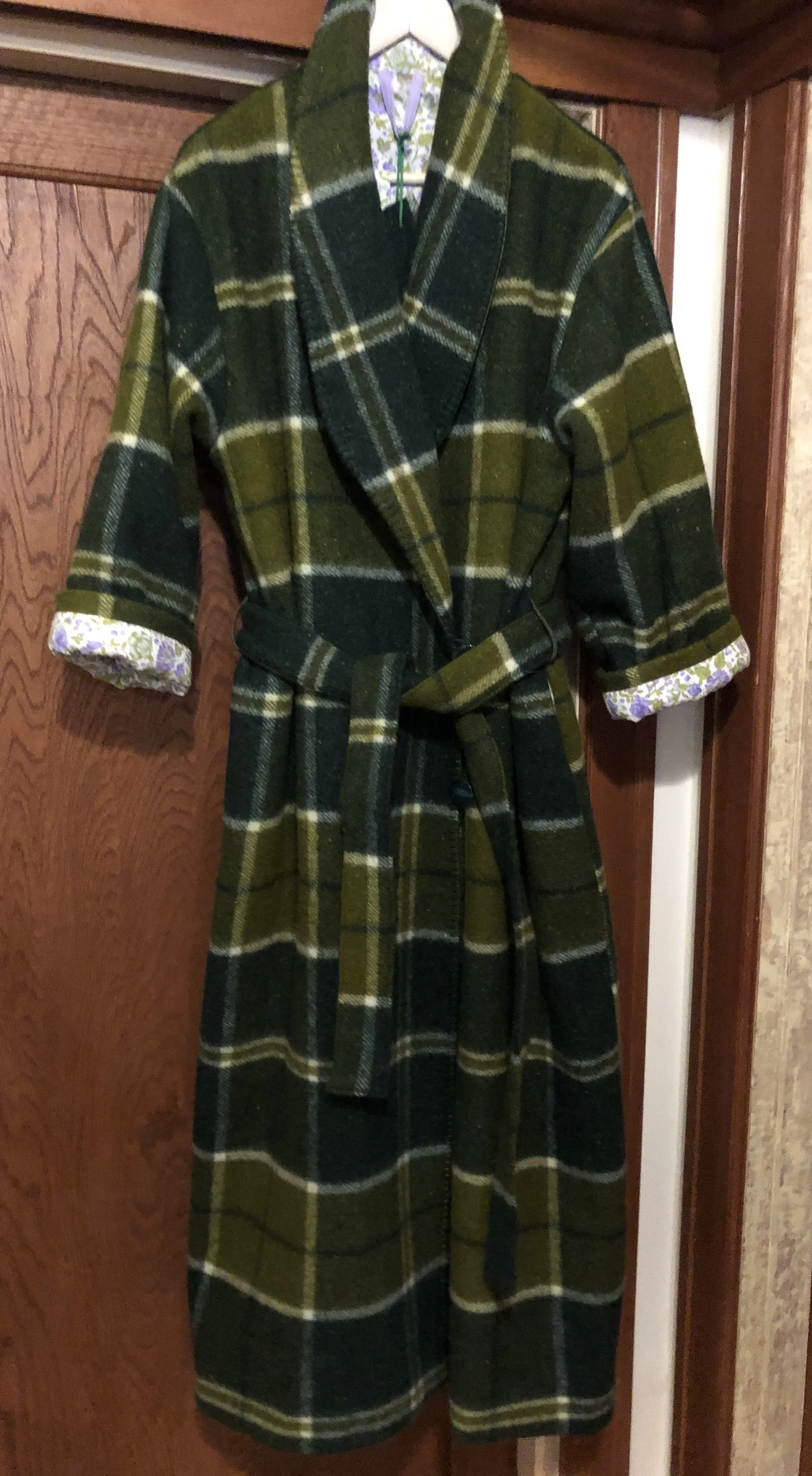 Green and Blackwood dressing robe with a belt, hanging on a wooden door. The coat has rolled-up sleeves with floral lining showing.
