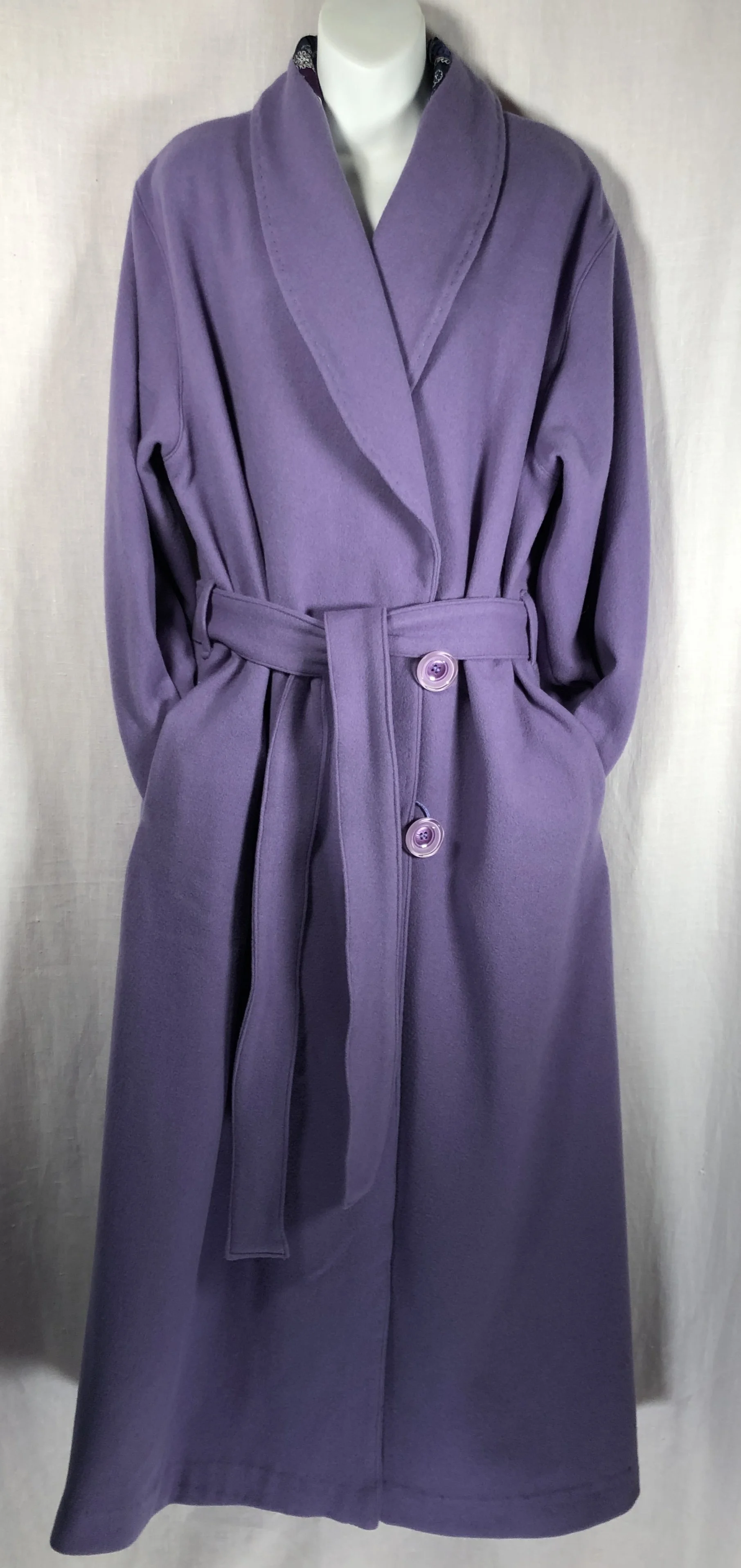 Purple wool dressing robe with a belt and large buttons hanging on a mannequin