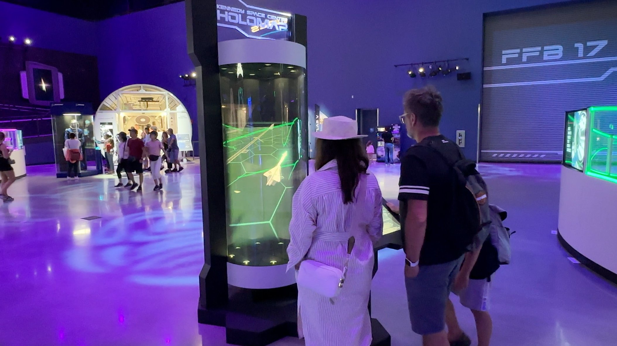    Visitors explore the HoloTube exhibit at Kennedy Space Center, engaging with the holographic map and the stories it tells.   