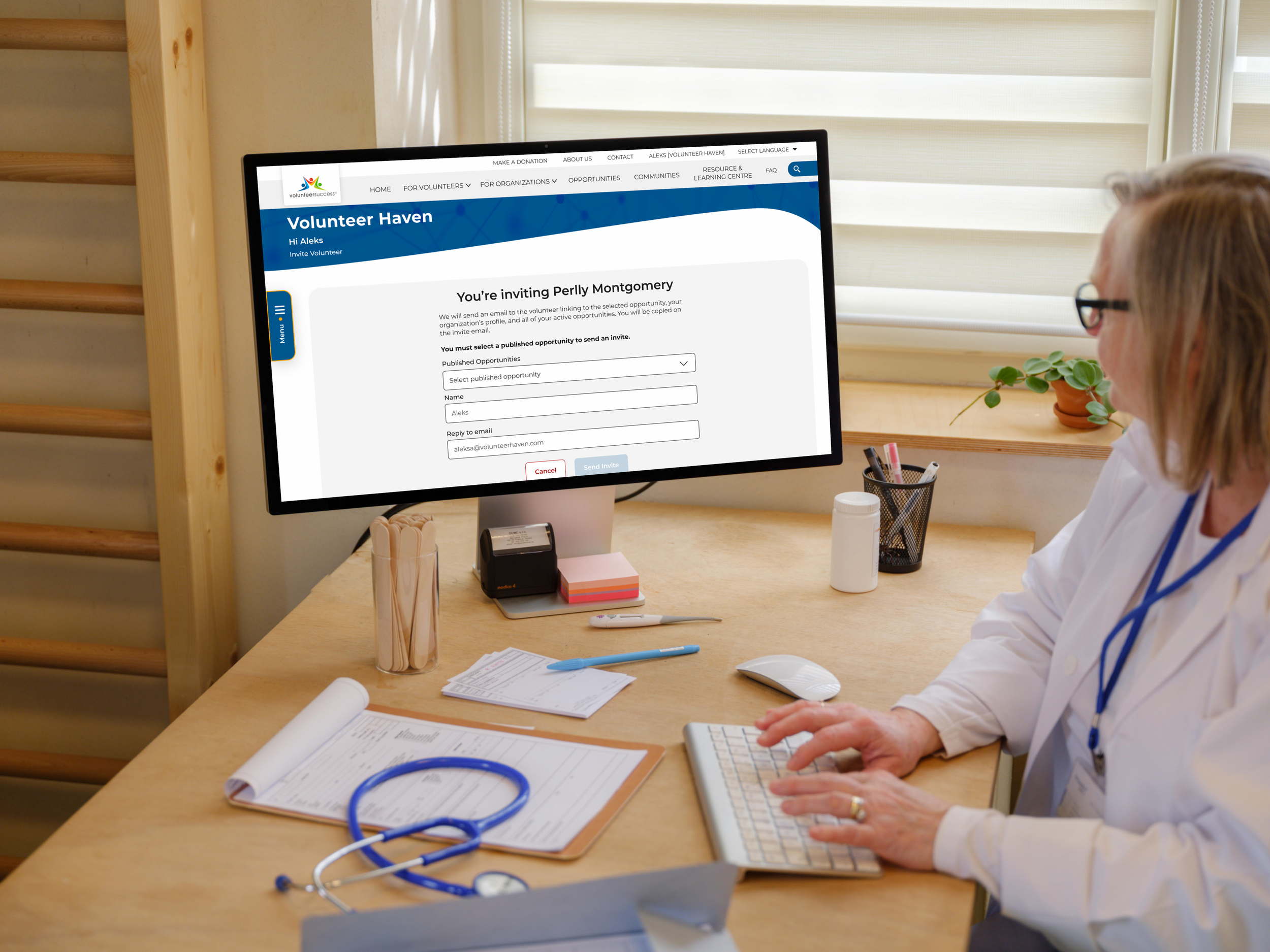 female doctor typing on an apple studio display with the browser on the invite volunteer page