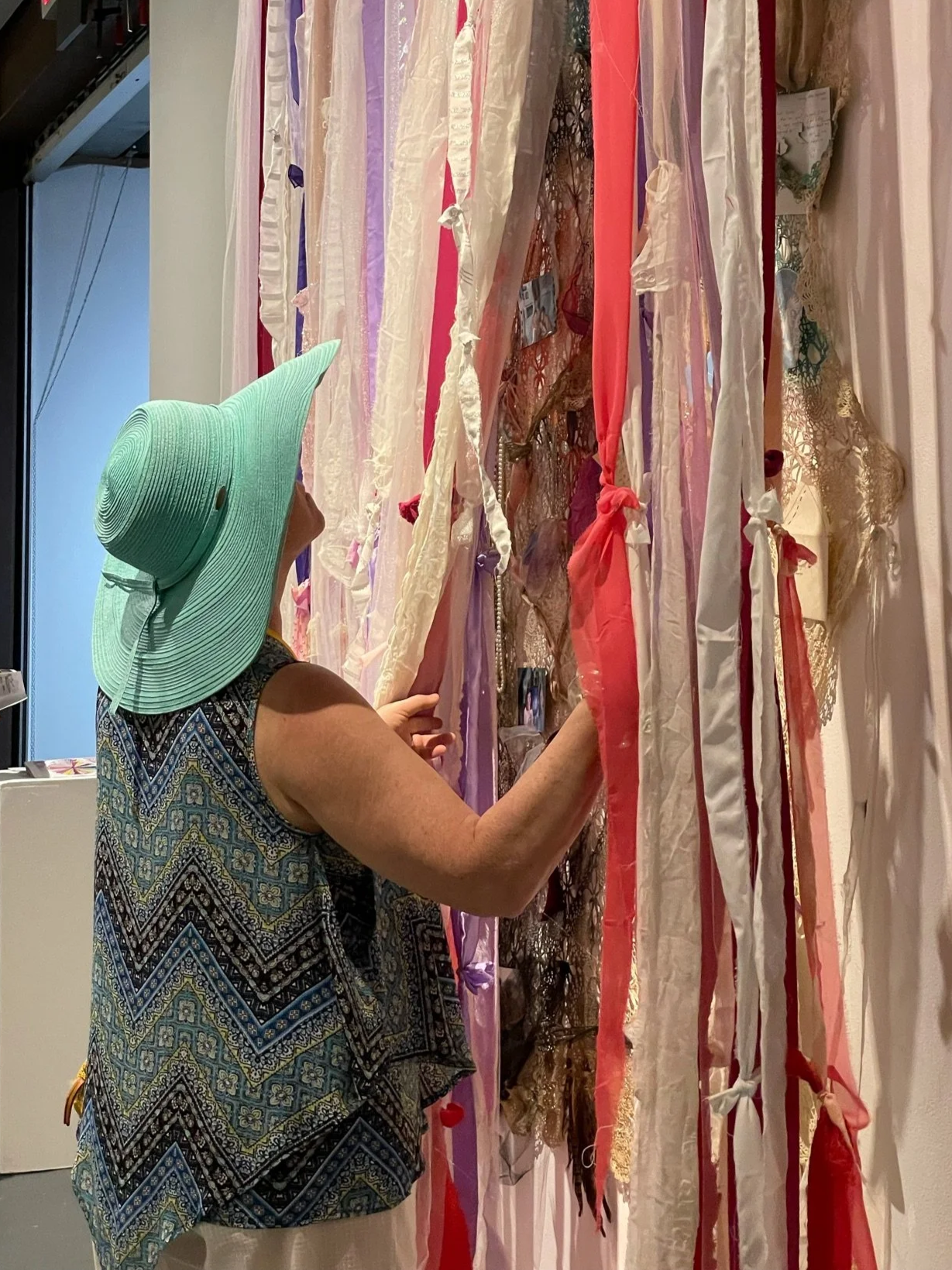 Audience interacting with layered veil installation concealing fabric collage beneath translucent textile.