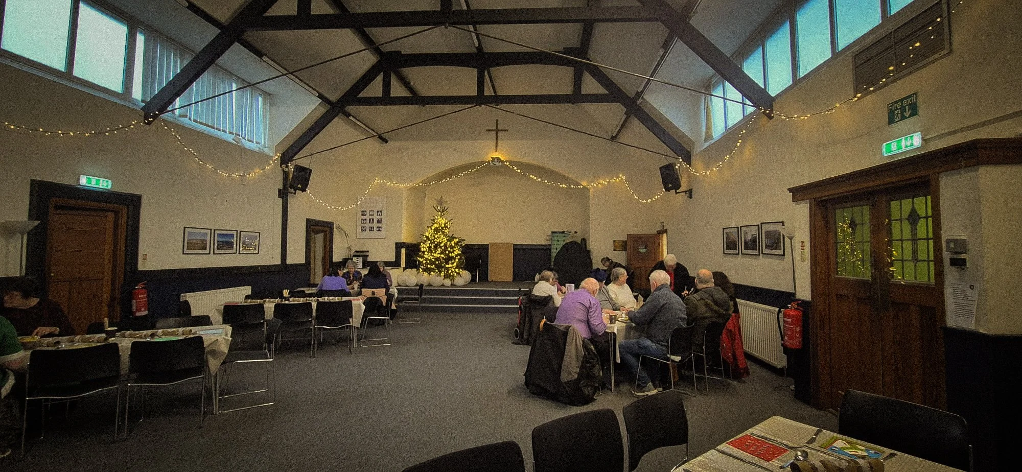 group of people mainly elderly sit around tables under twinkling lights for a Christmas meal at Redcar Baptist Church. A lovely evening to those who would otherwise be spending Christmas alone.