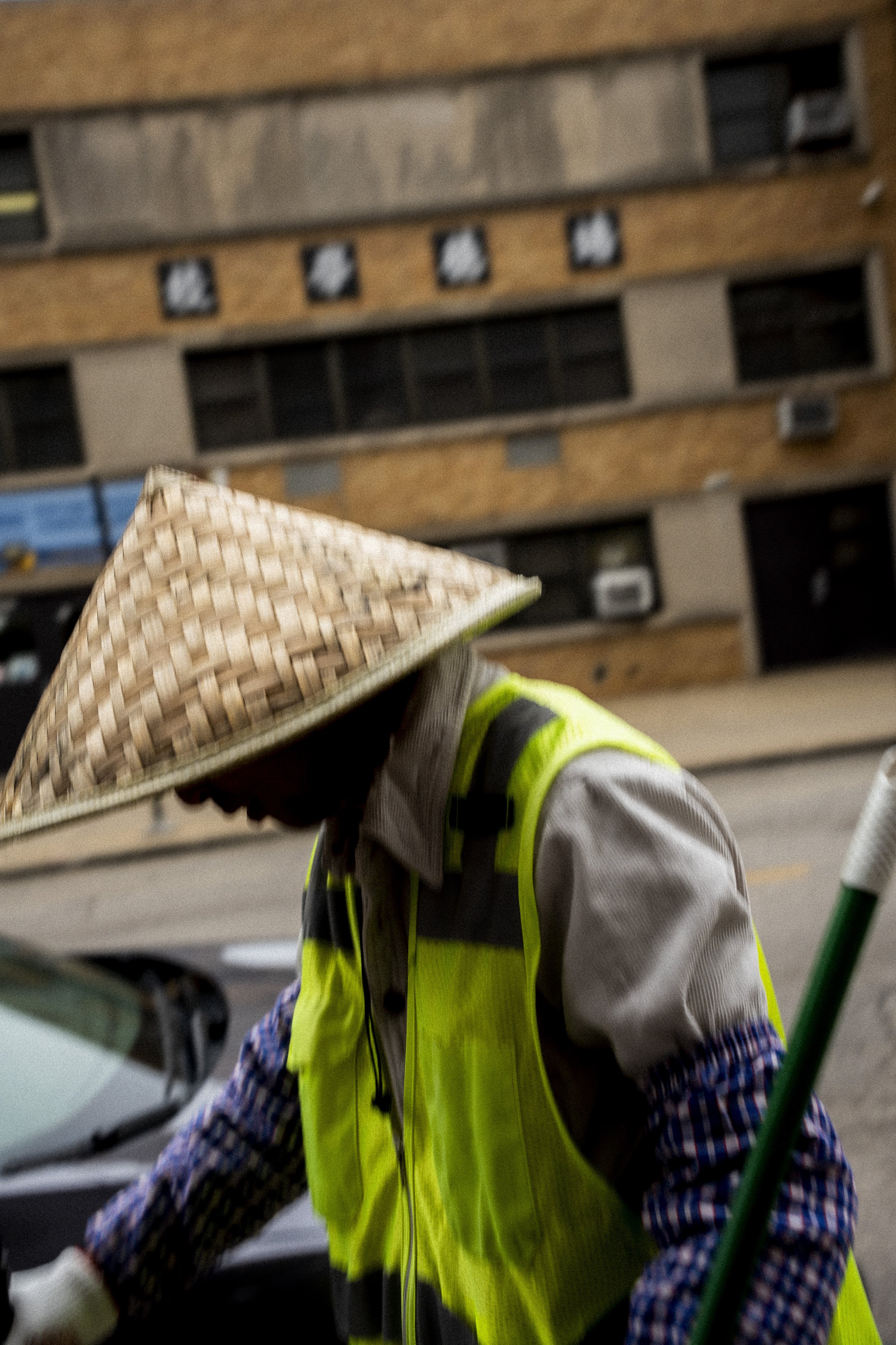Close-up photograph of a Chinatown, Chicago street worker wearing a conical hat and reflective vest in Chicago.