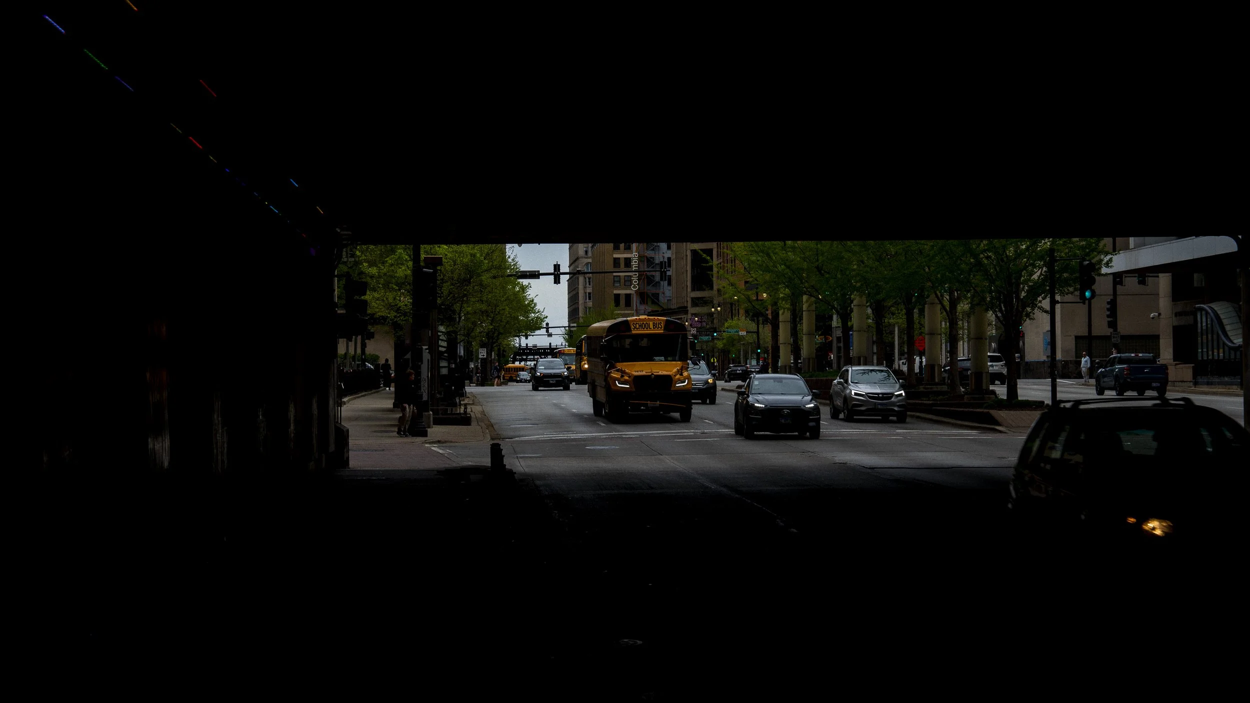 School bus approaching on a downtown Chicago street, viewed from inside a dark tunnel.