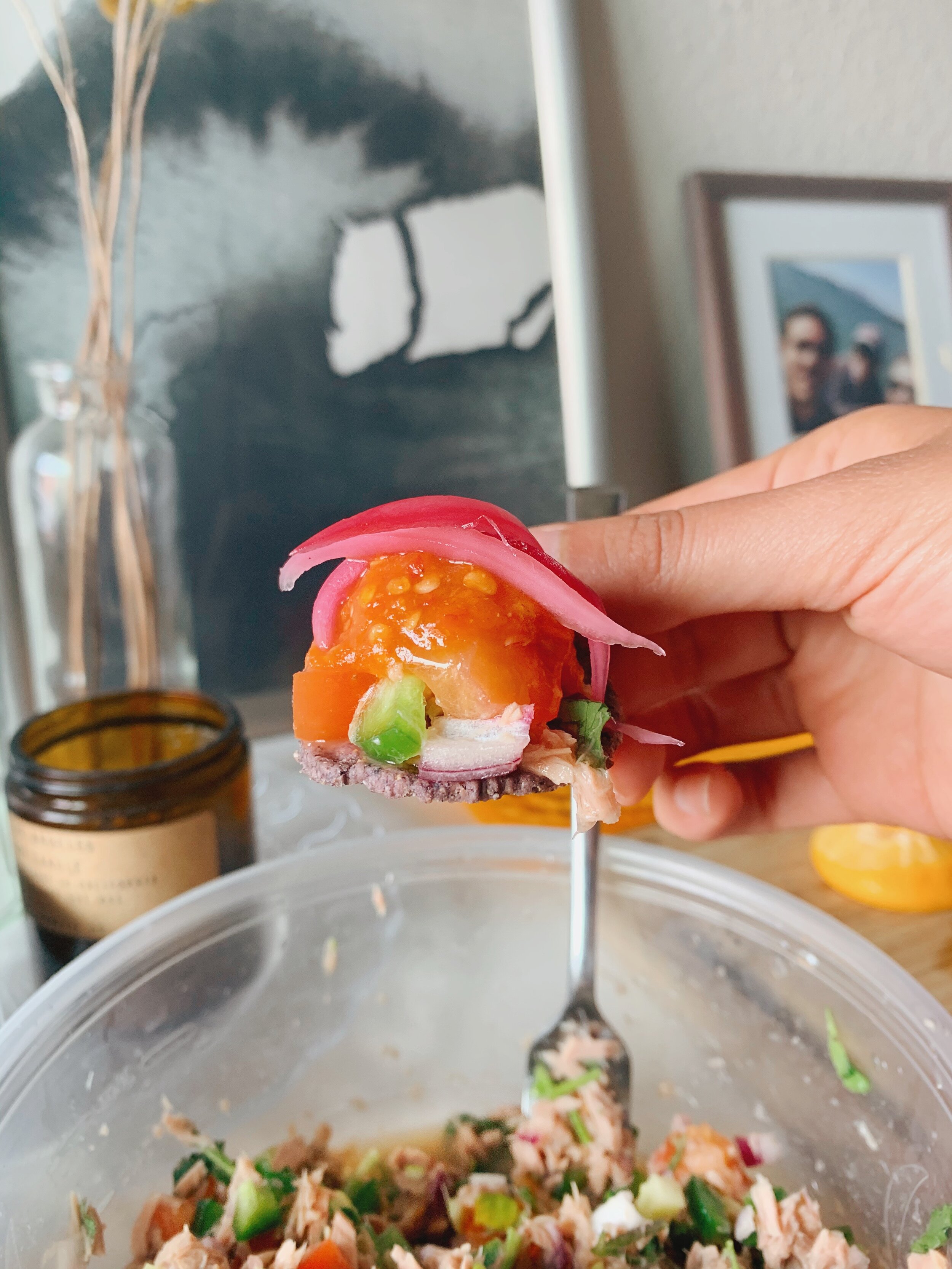 Tuna ceviche on a tortilla chip, topped with pickled onions and salsa