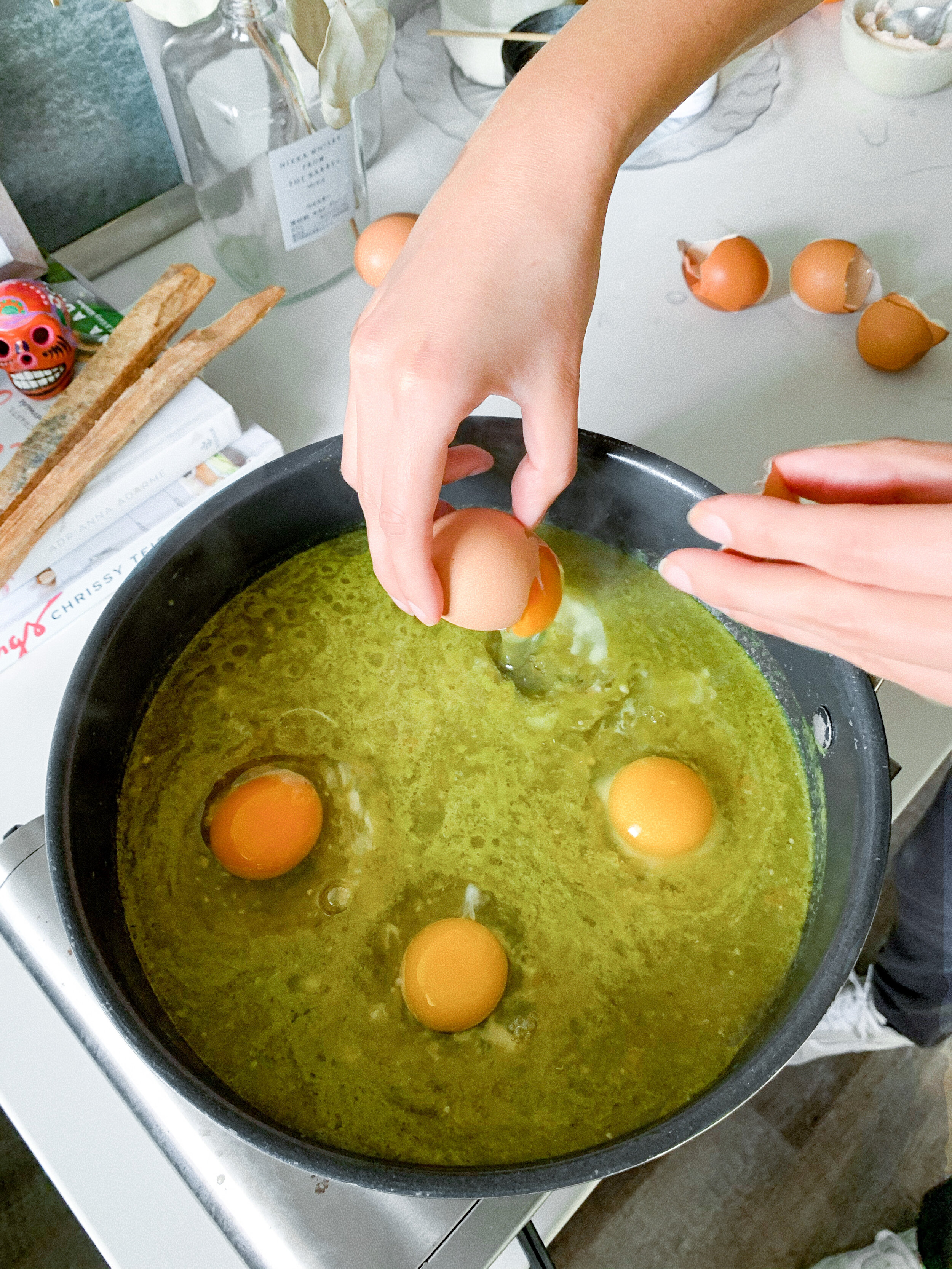 Cracking each egg into the salsa verde