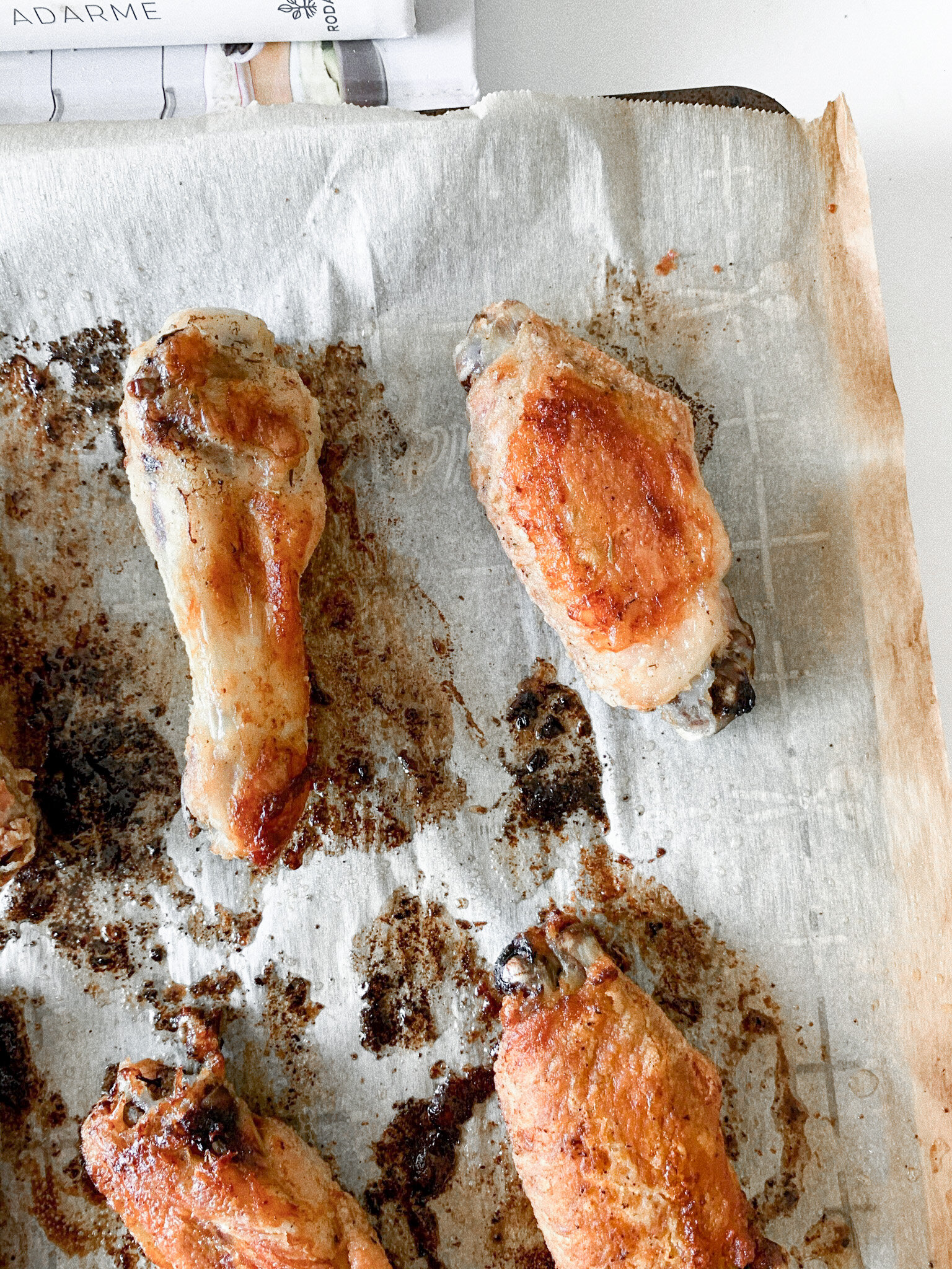 Freshly baked chicken wings on a parchment lined baking sheet