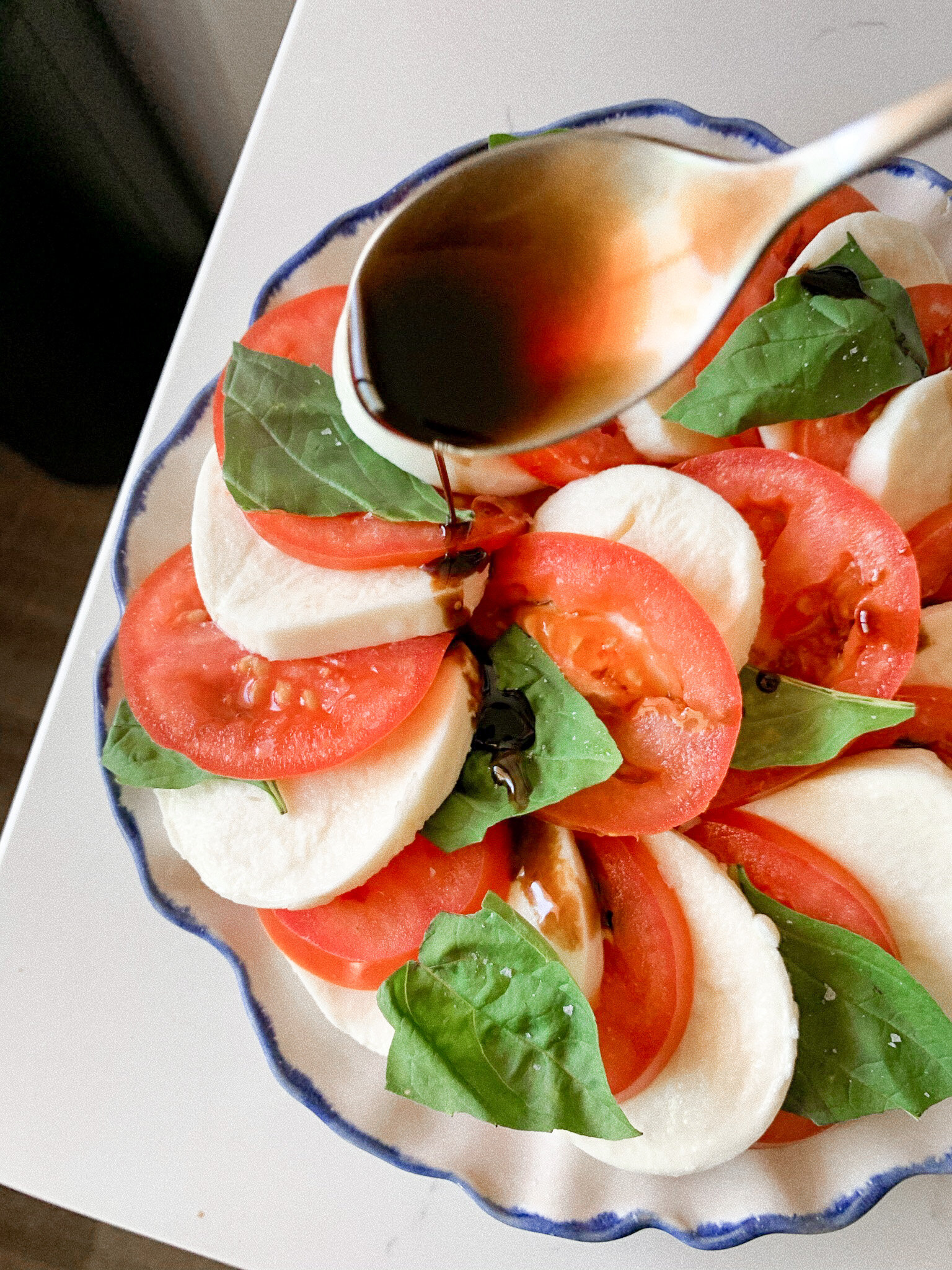 Pouring the homemade balsamic glaze over the caprese salad