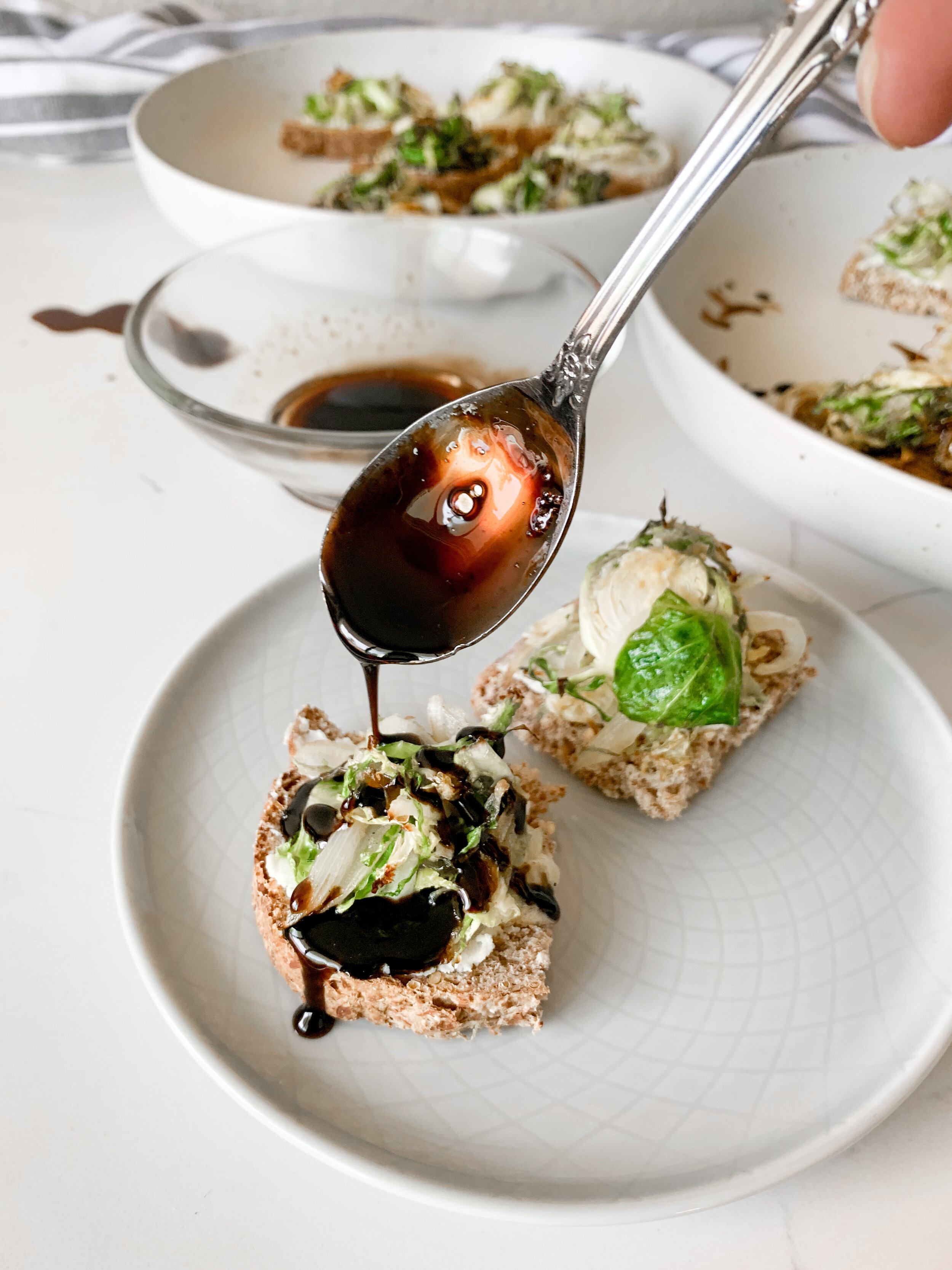 Pouring the balsamic glaze over the brussels sprout pizza bites