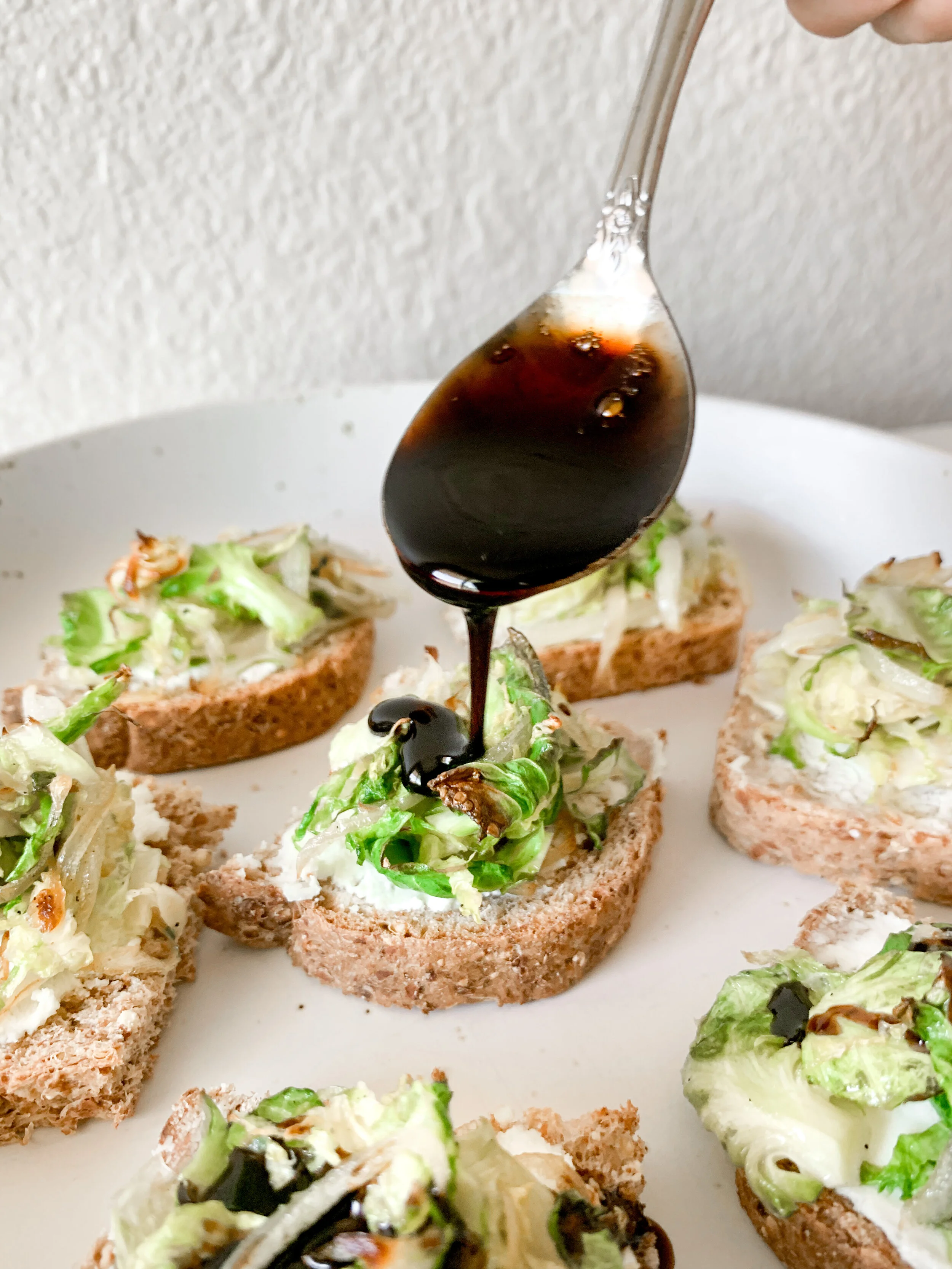 Pouring the balsamic glaze over the brussels sprout pizza bites