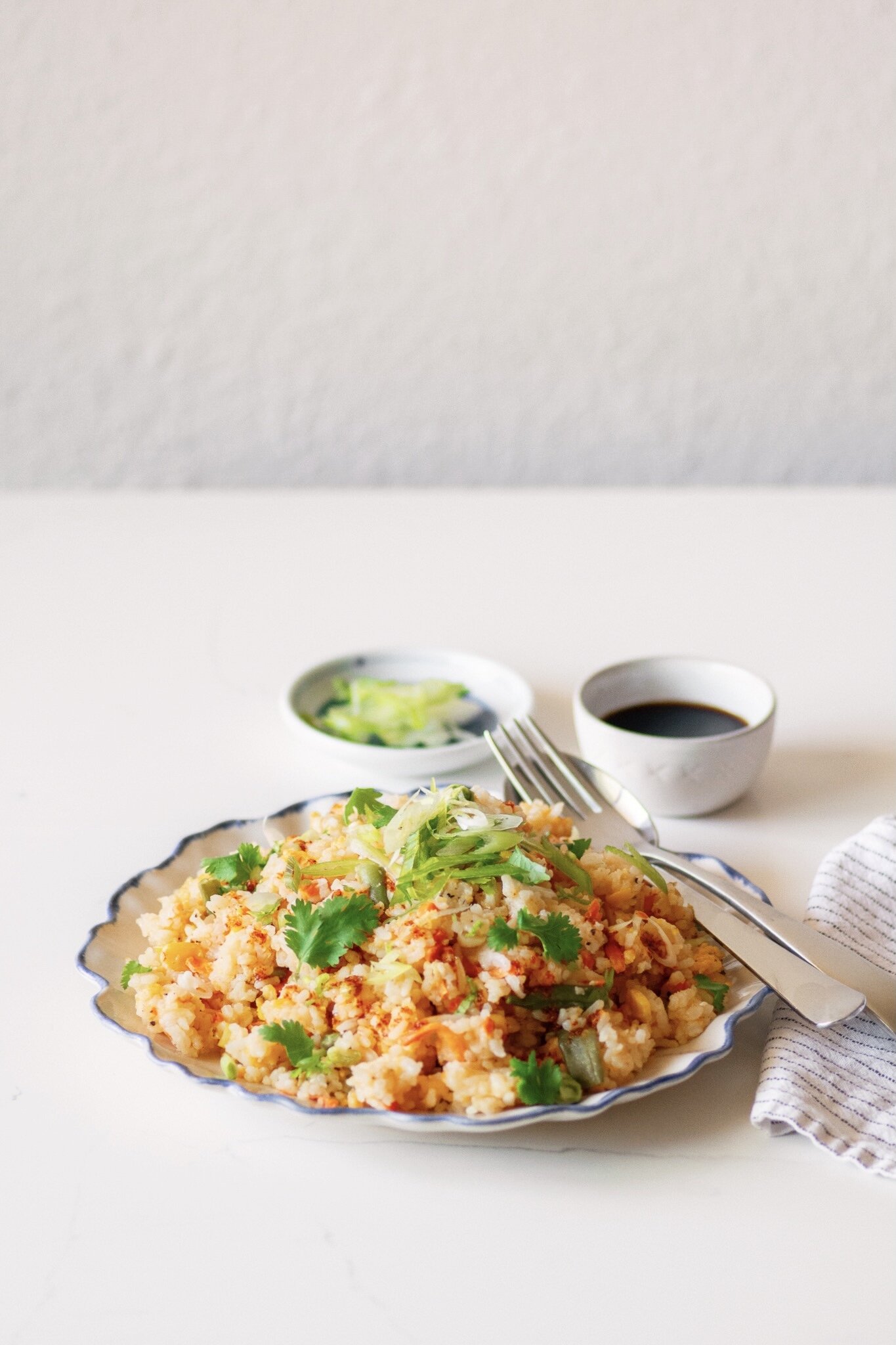 Plated Vegetable Fried Rice garnished with sliced scallions, cilantro and chili oil.