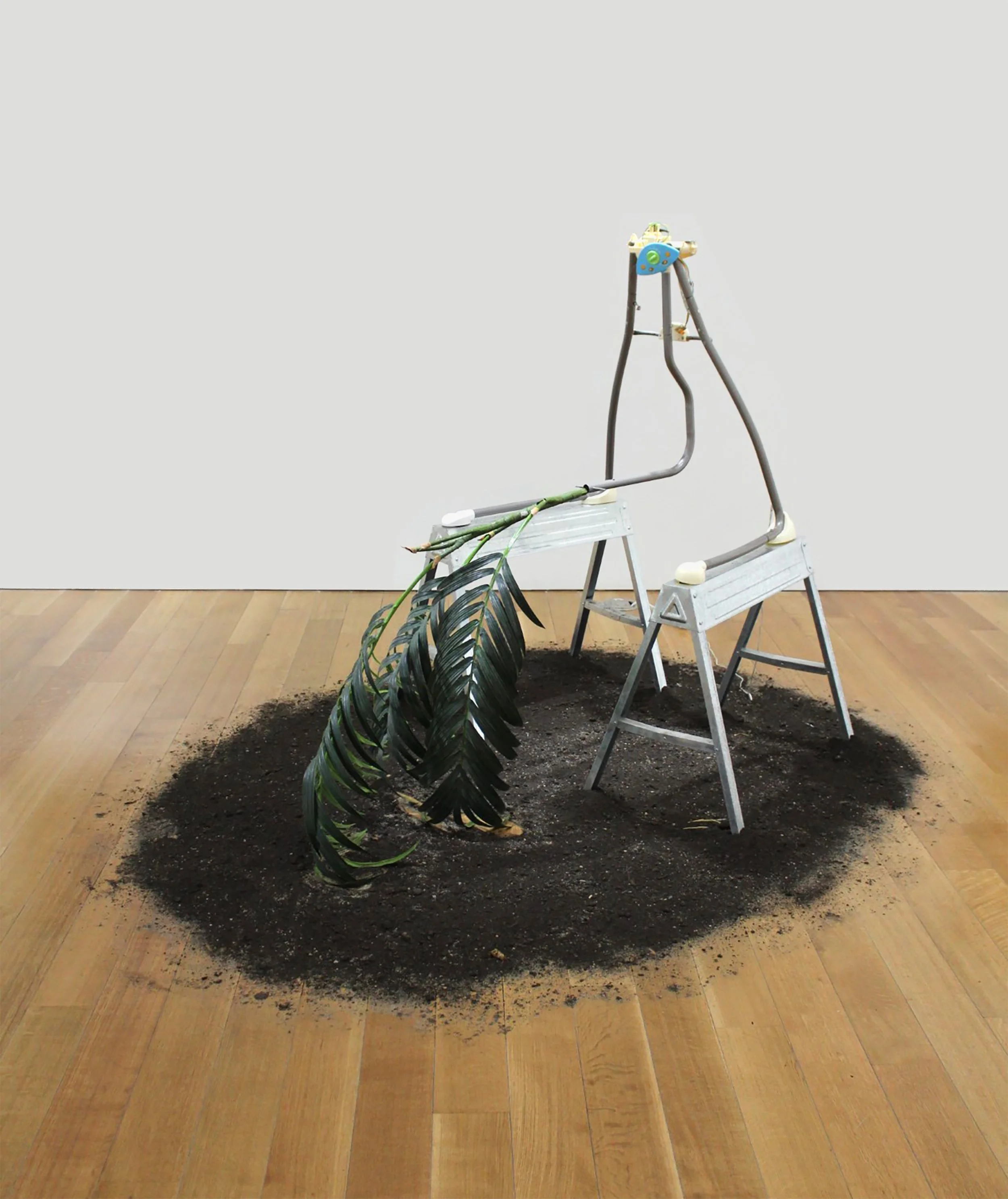 Rachel Youn,  Pendulum,  2022, Dismantled baby swing, steel saw horses, artificial plant, soil, 68 x 80 x 92 in.