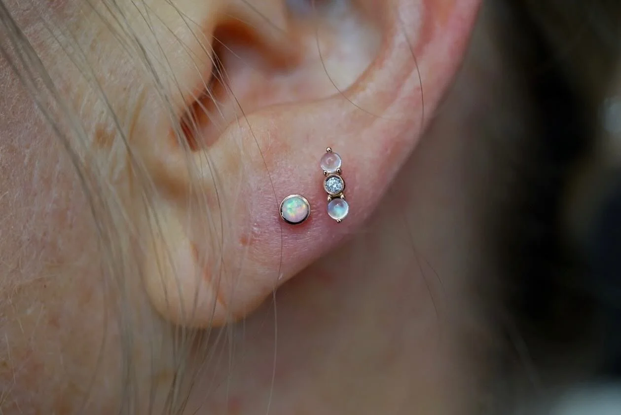 Pair of lobe piercings for Emily from yesterday! So stocked on seeing these tops together! &ldquo;Revel&rdquo; (stack of Rainbow Moonstones featuring a White CZ set in Rose Gold) from @emberbodyjewelry paired with a 2.5 White Opal cabochon also set i