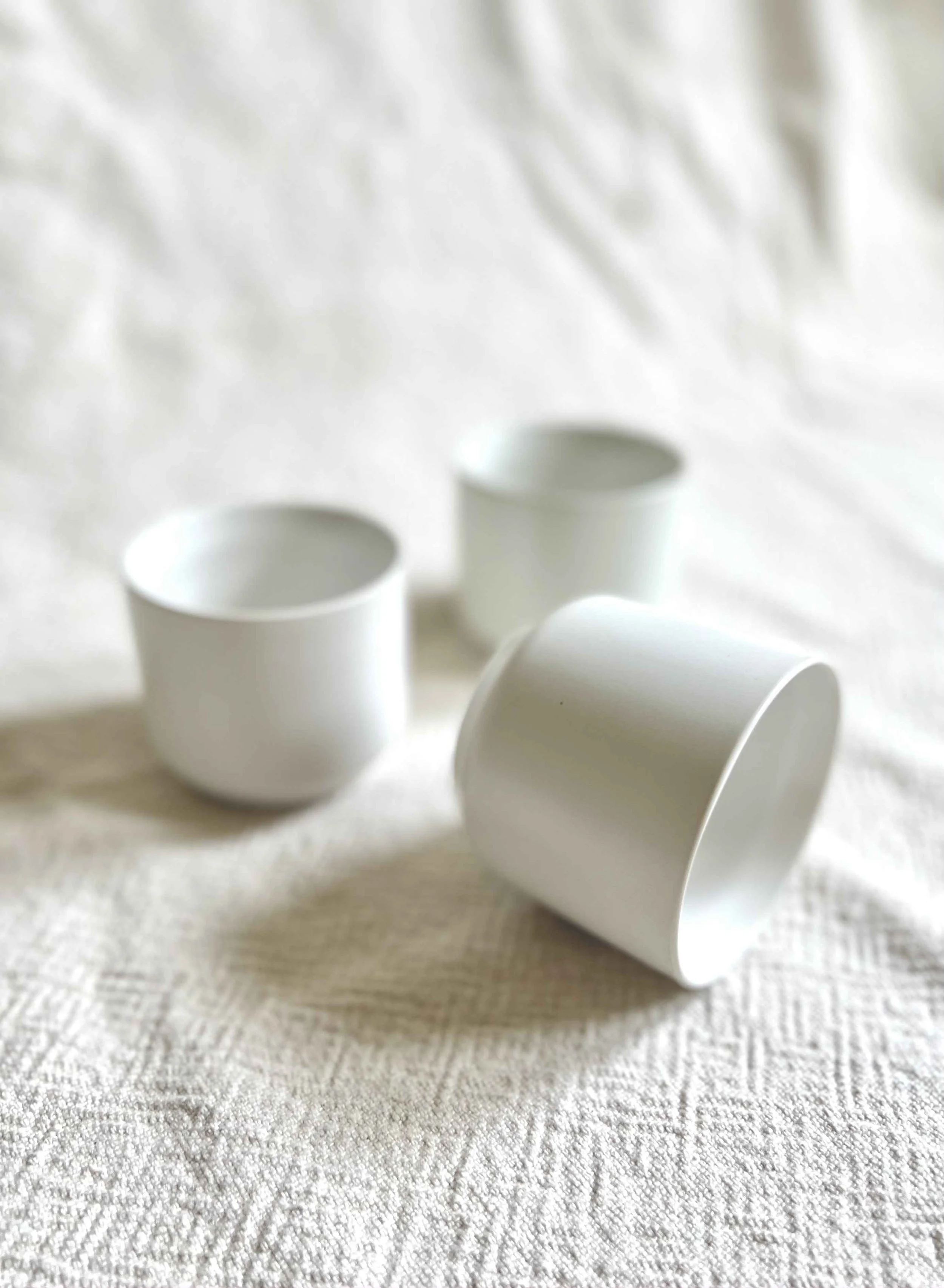 Three basic small matte white ceramic cylindrical vases.