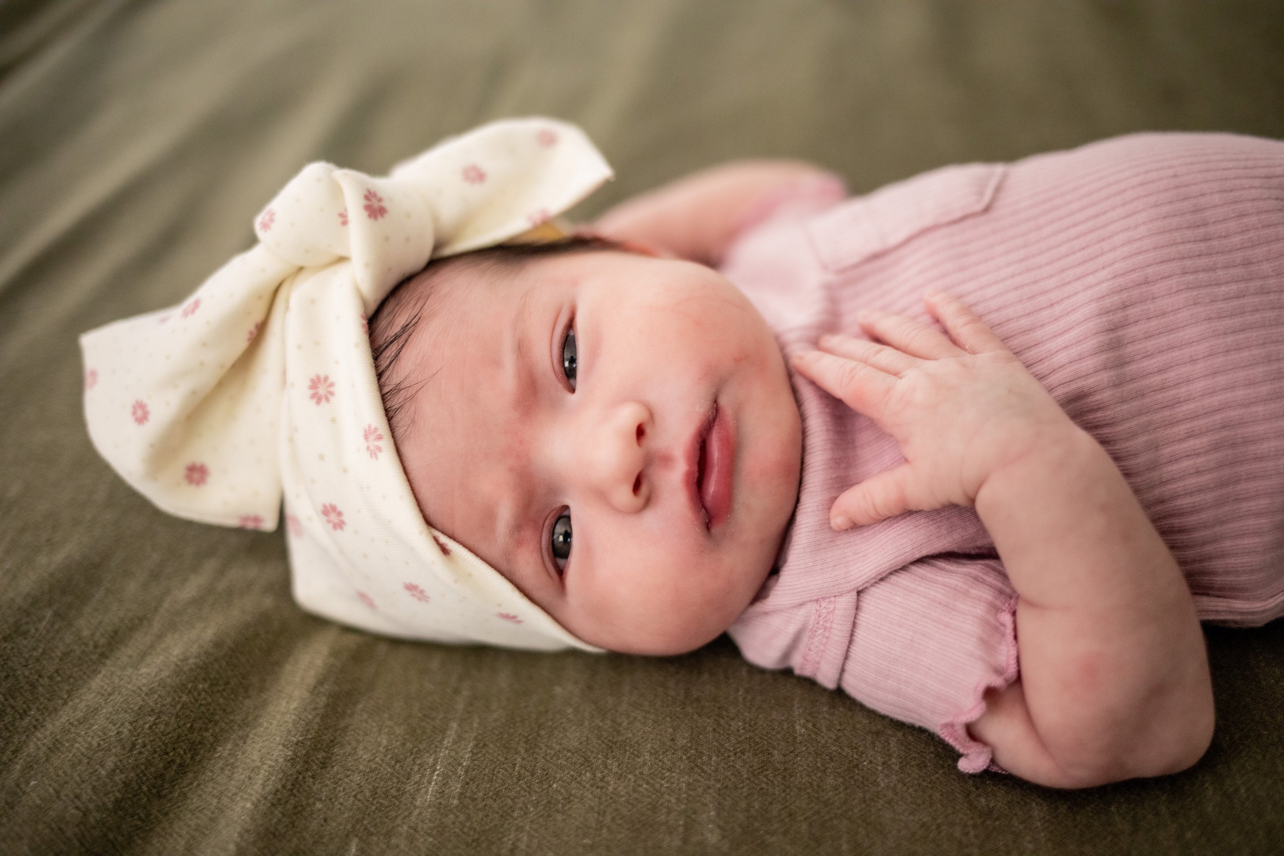 new born baby wearing a white bow and a pink onesie
