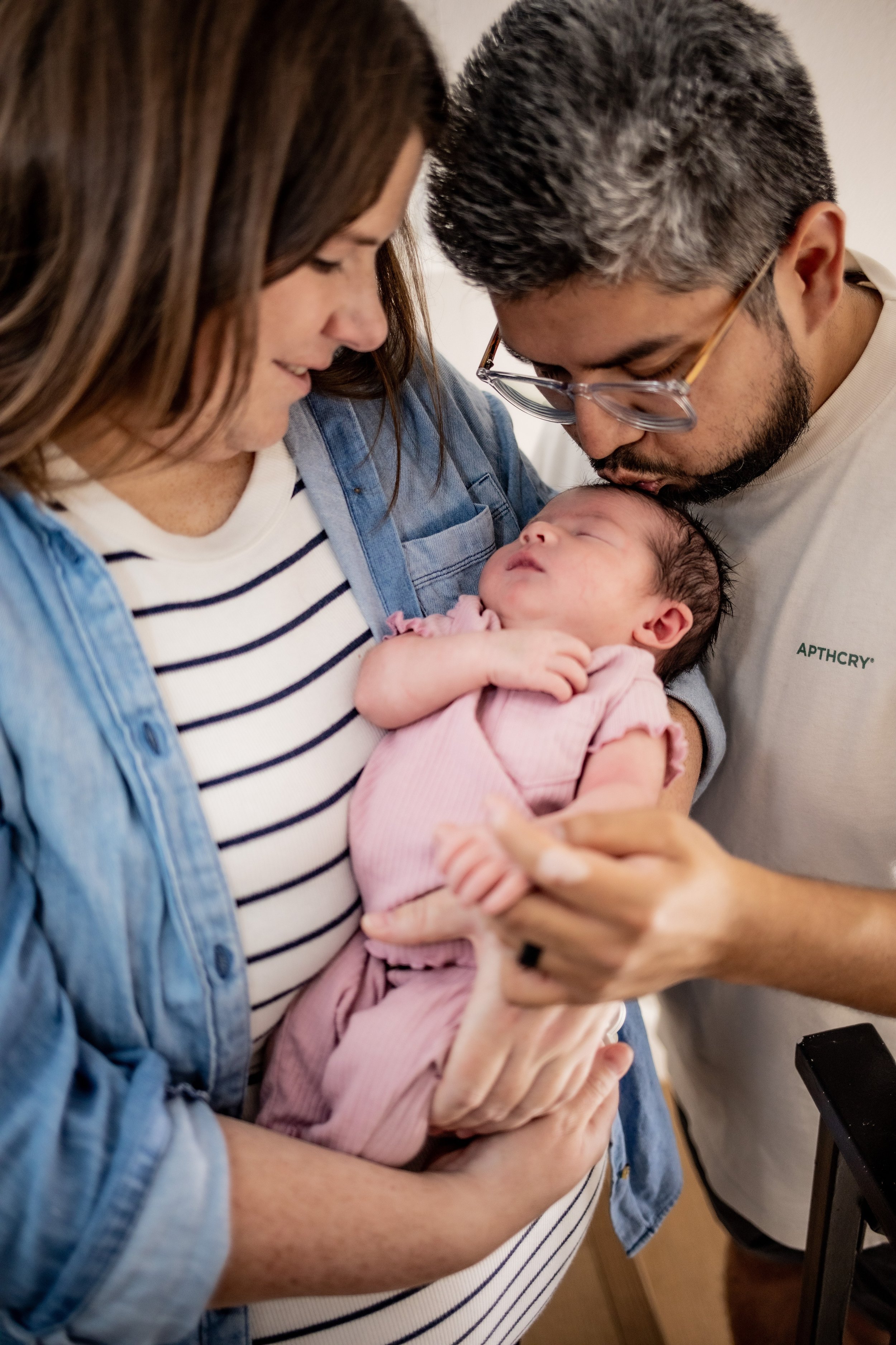 parents holding new born baby in a pink onsie
