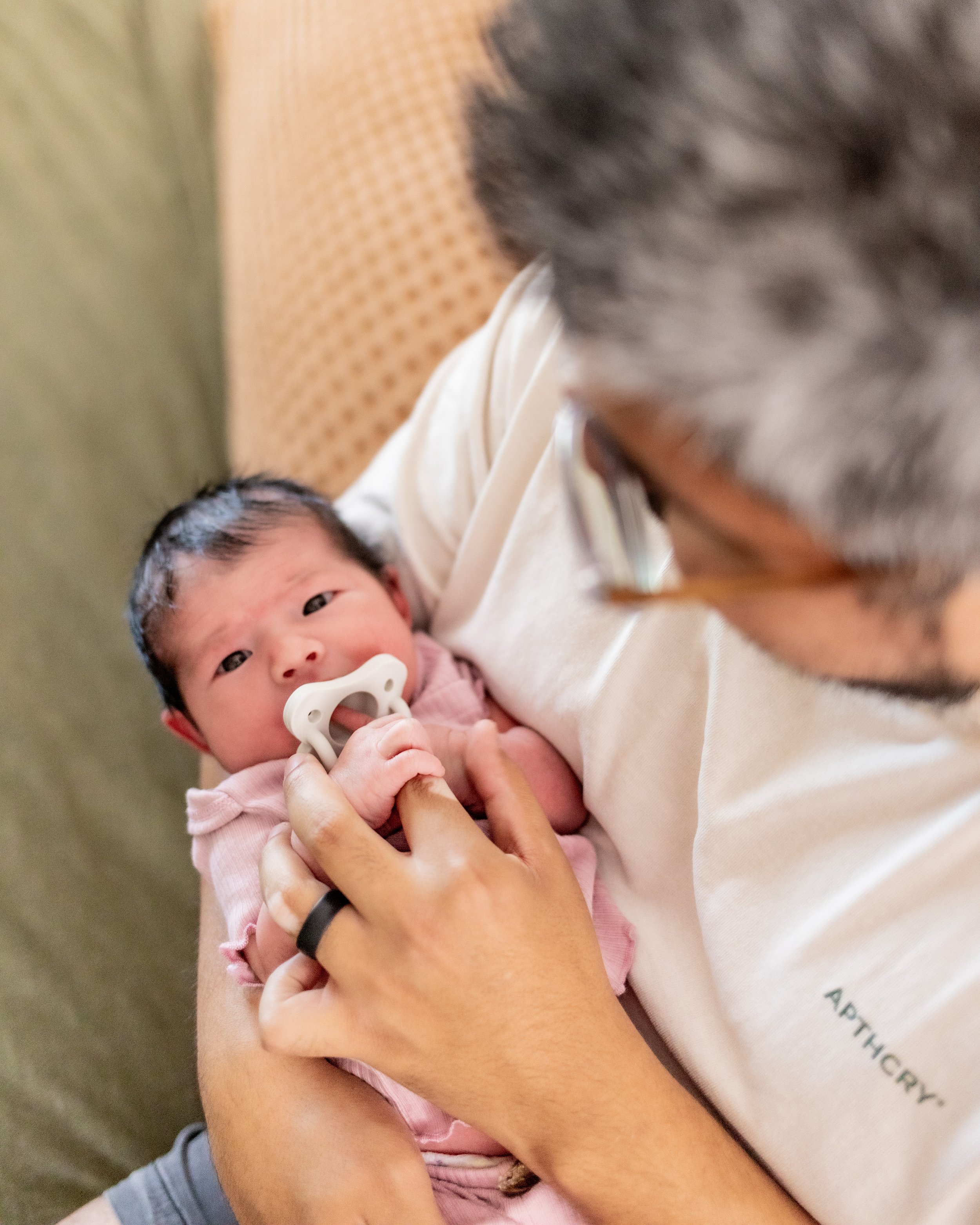 father holding baby in a pink onesie