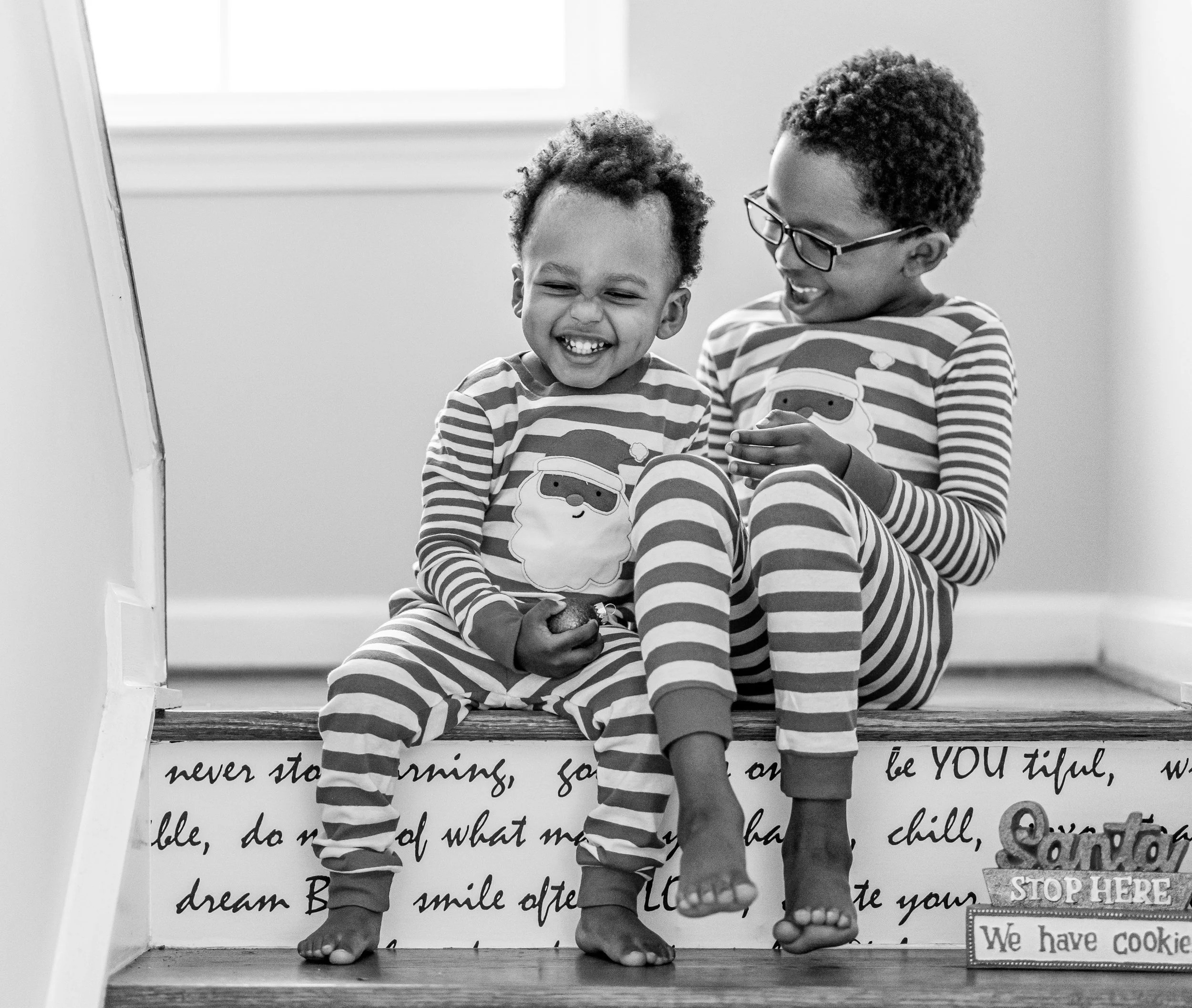 Two siblings sitting on stairs, showing a warm, playful bond.