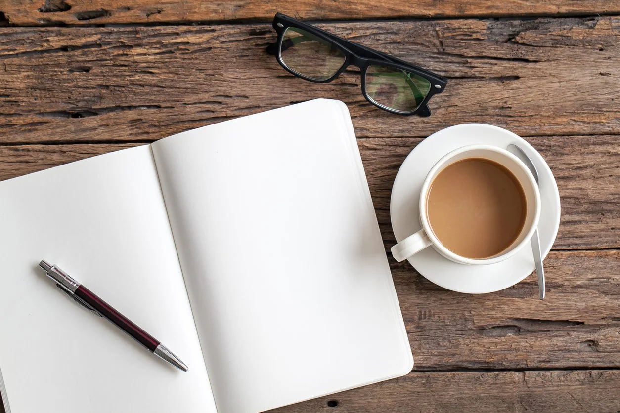 A notepad, pen, and cup of coffee to show how notetaking during parenting therapy can help.