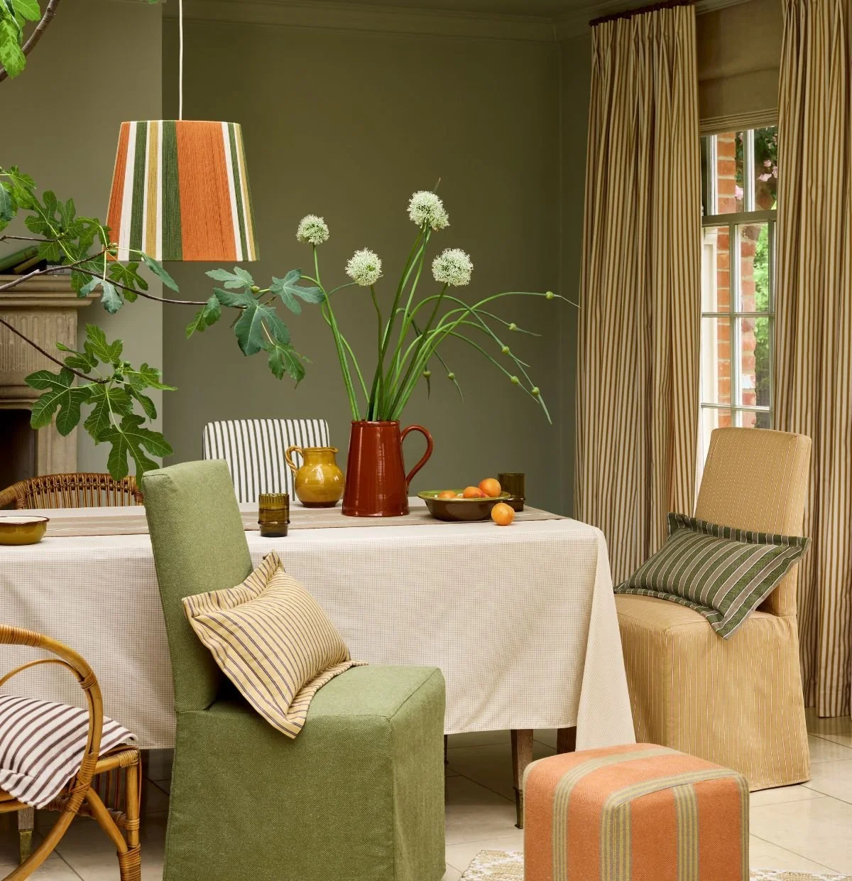 Ian Mankin Beacons Collection fabrics featuring striped curtains, upholstery and cushions in a layered green dining room.