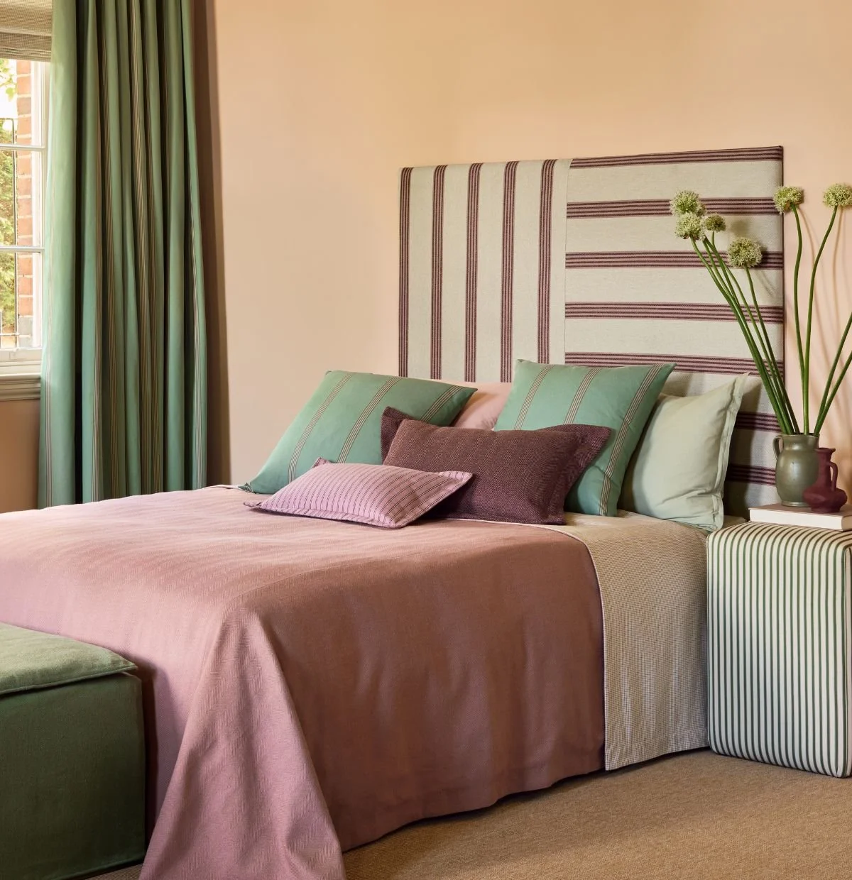 Ian Mankin Beacons Collection striped fabrics in a layered bedroom scheme with upholstered headboard, cushions, curtains and soft furnishings.