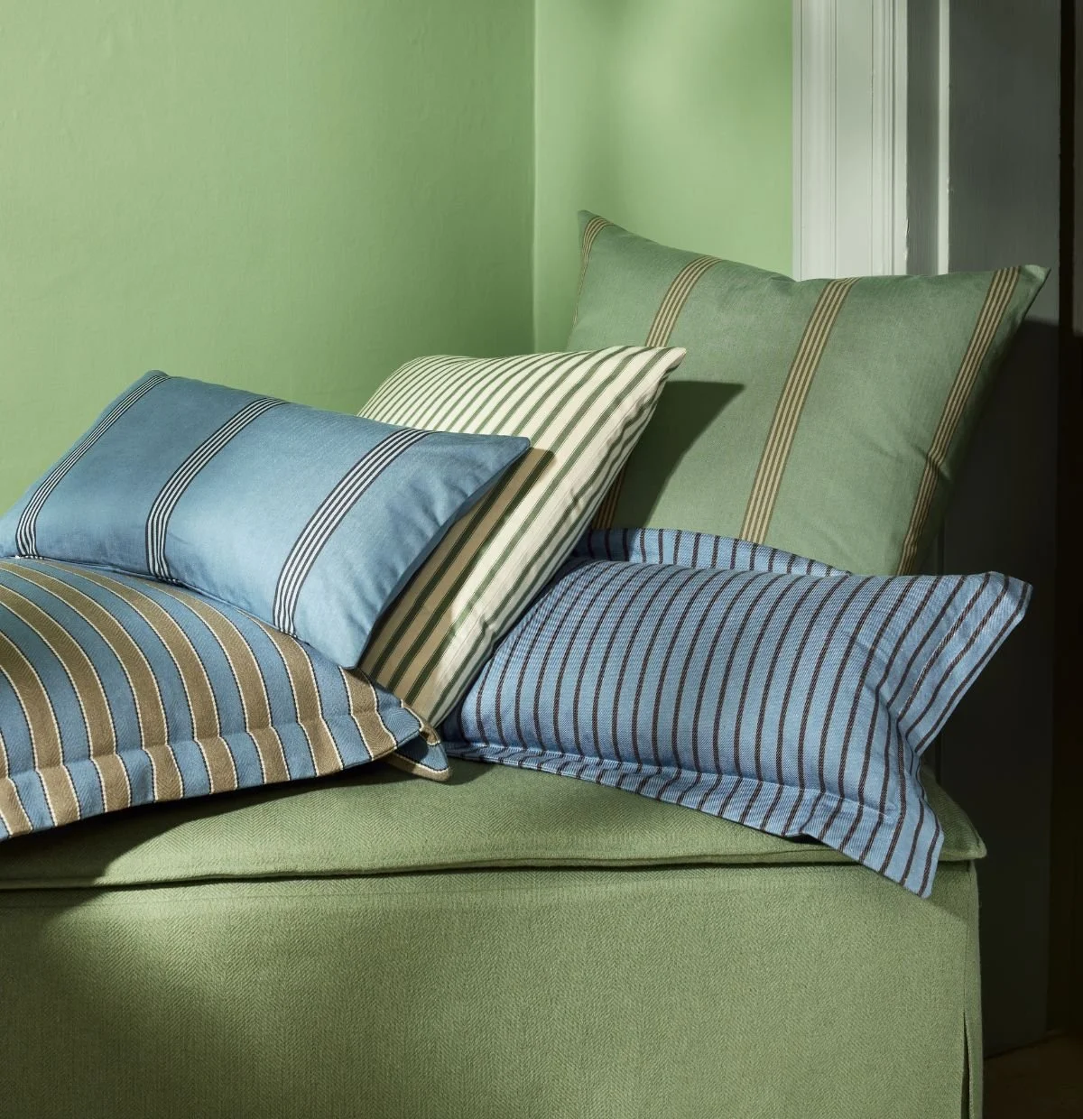 Ian Mankin Beacons Collection striped cushions in blue, green and natural tones layered in a contemporary interior.