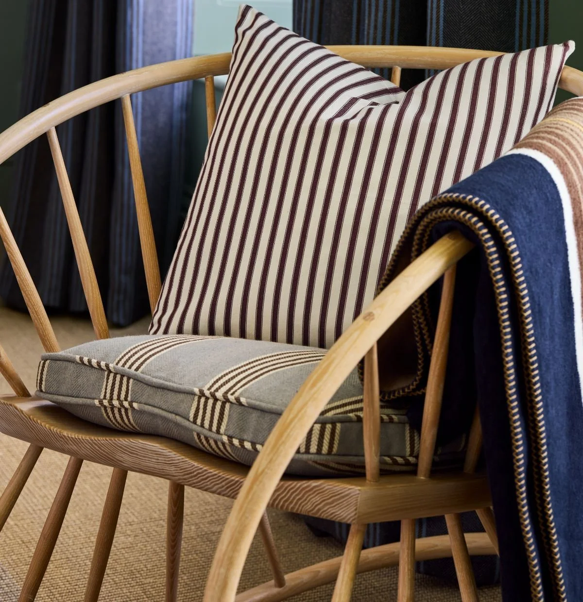 Ian Mankin Beacons Collection striped fabrics layered across cushions and upholstery on a timber chair.