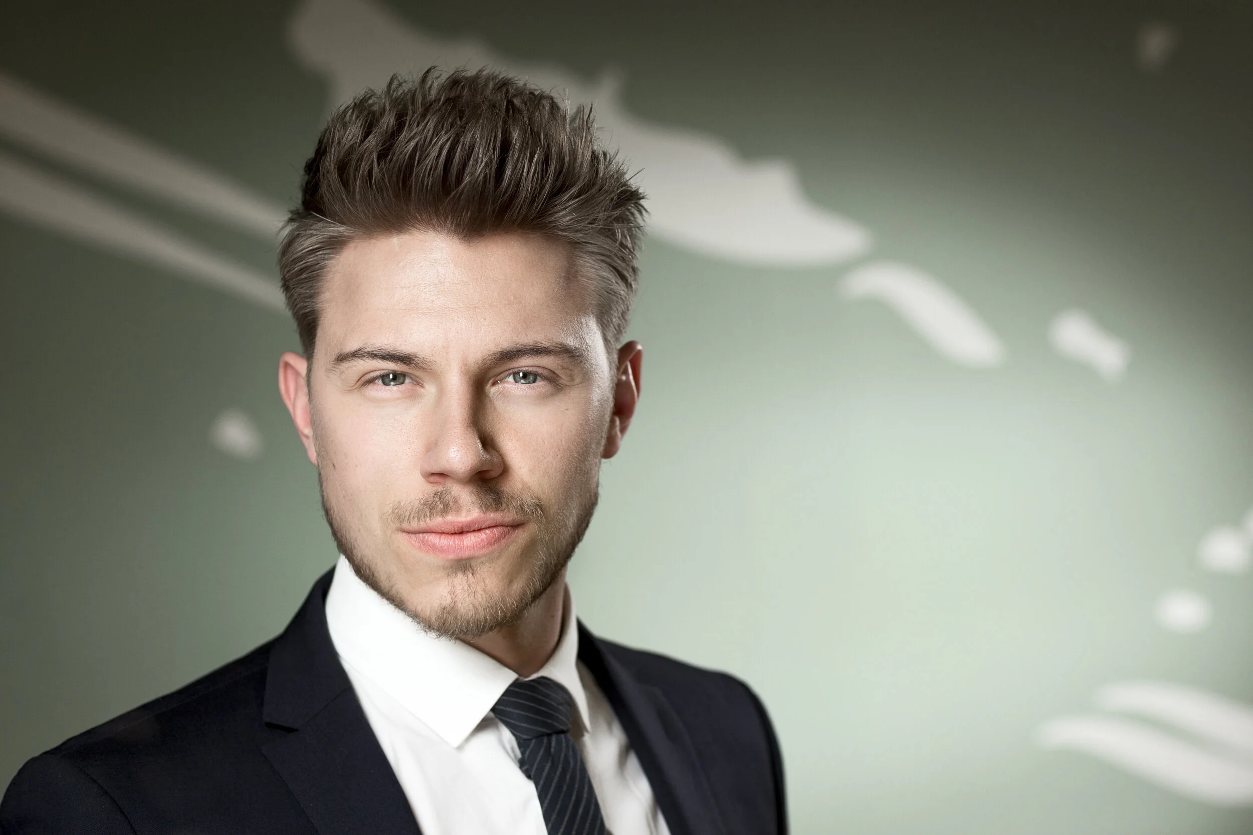 Knivskarpt headshot af fokuseret mand I jakkesæt, skarp belysning, ved Steen Brogaard.
