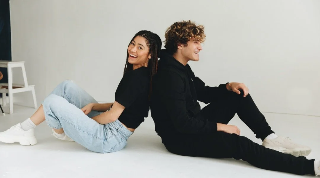 Two people wearing black Hexed loungewear smiling and sitting on the ground