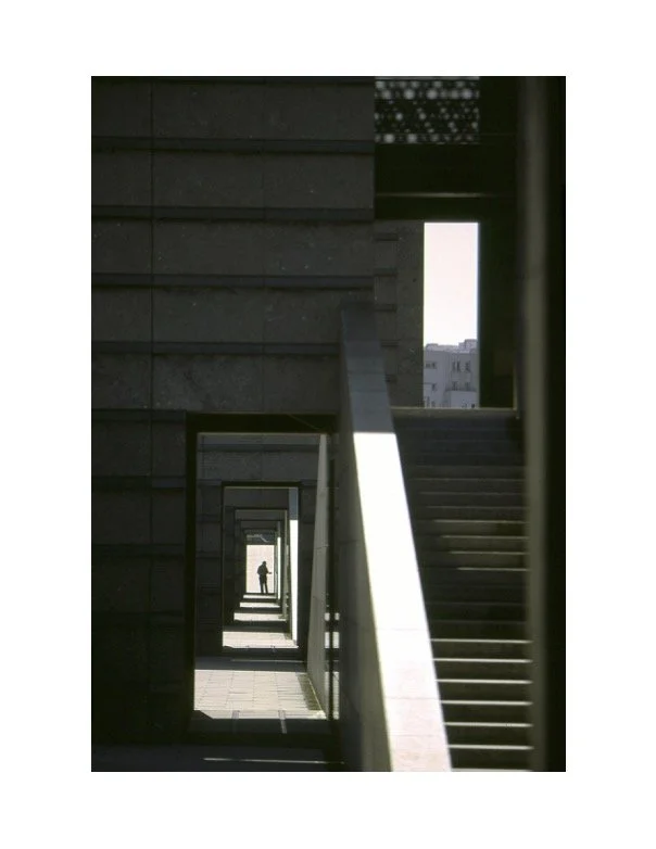 black and white photograph of a stairwell and a corridor with a person silhouetted in the far distancw