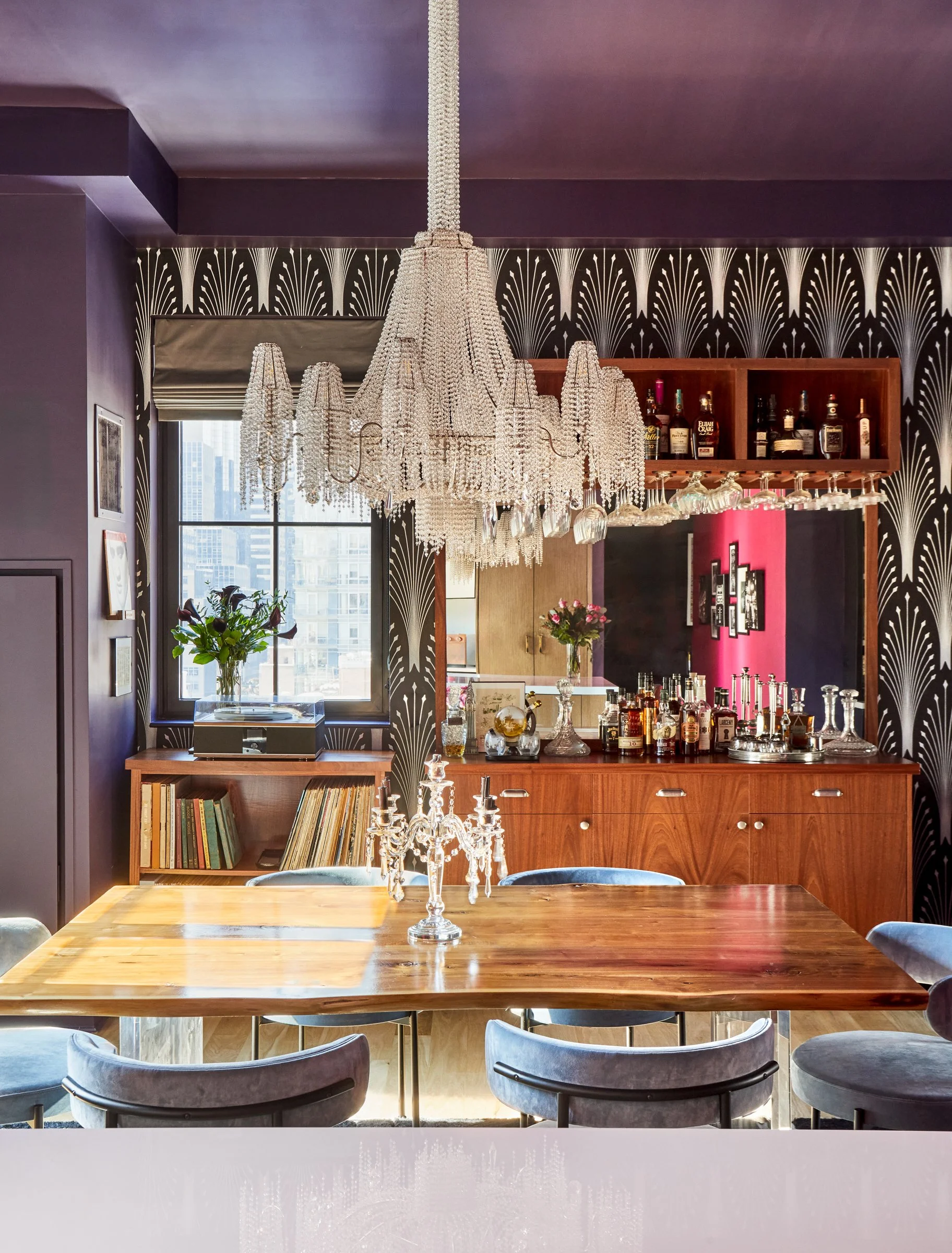 sparkly crystal chandelier hangs brightly over live edge dining table in open floor plan apartment in NYC