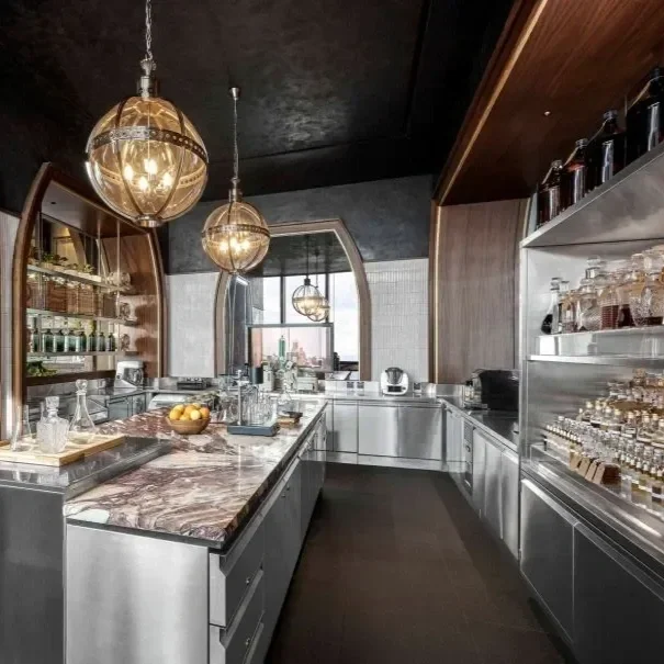 Cocktail laboratory at Artesian Jakarta rooftop bar with a marble countertop, mixology machinery, globe pendant lights, stainless steel worktop and shelving with laboratory glassware and bottles. Bar logistics designed by Studio Numen.