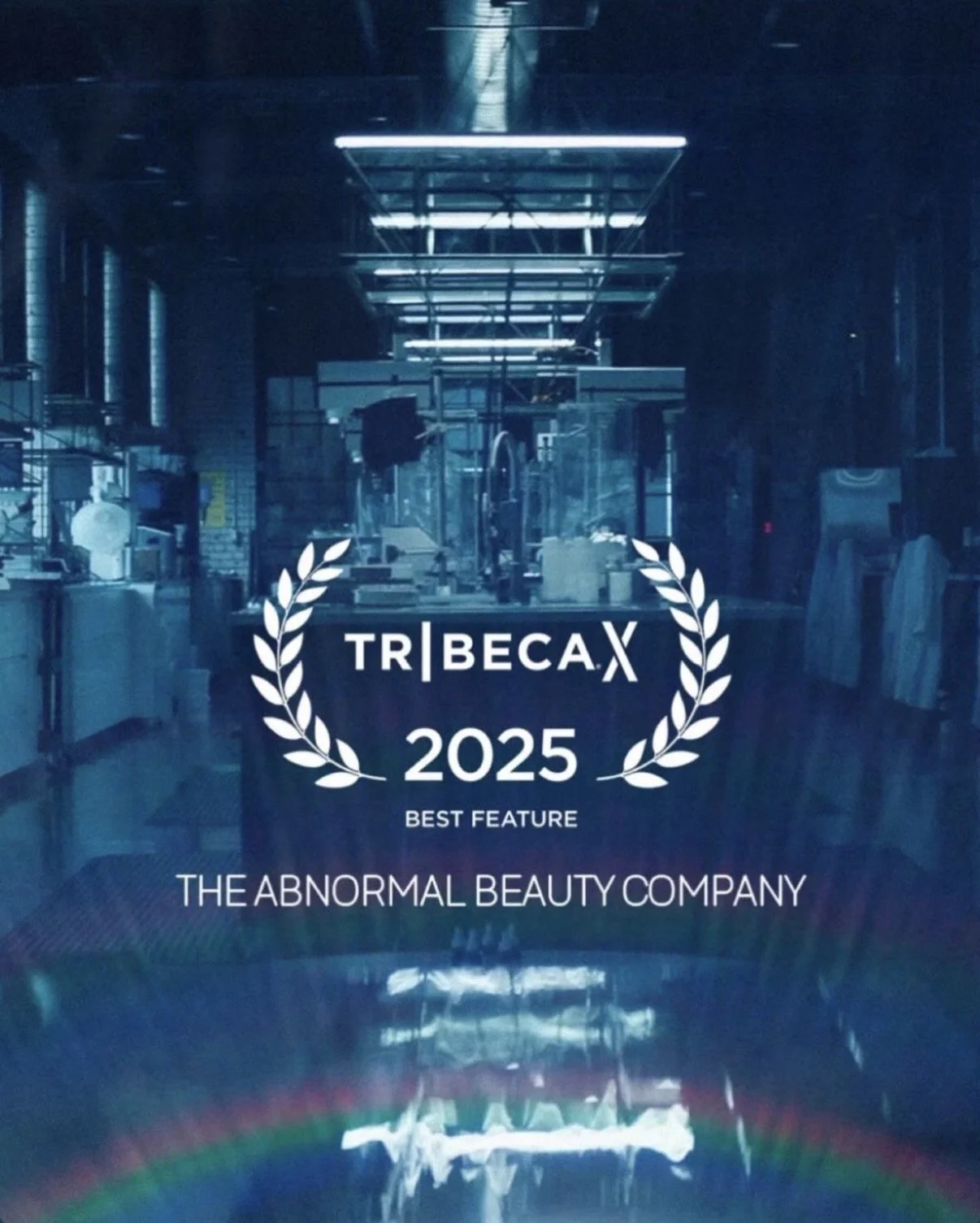 A glass door with the logo of Tribeca 2025, a film festival, and the slogan 'Best Feature' for The Abnormal Beauty Company, with a faint rainbow reflection at the bottom.