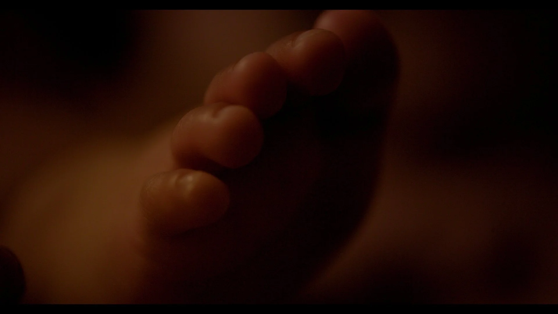Close-up of a hand with slightly curled fingers, minimal lighting, dark background.