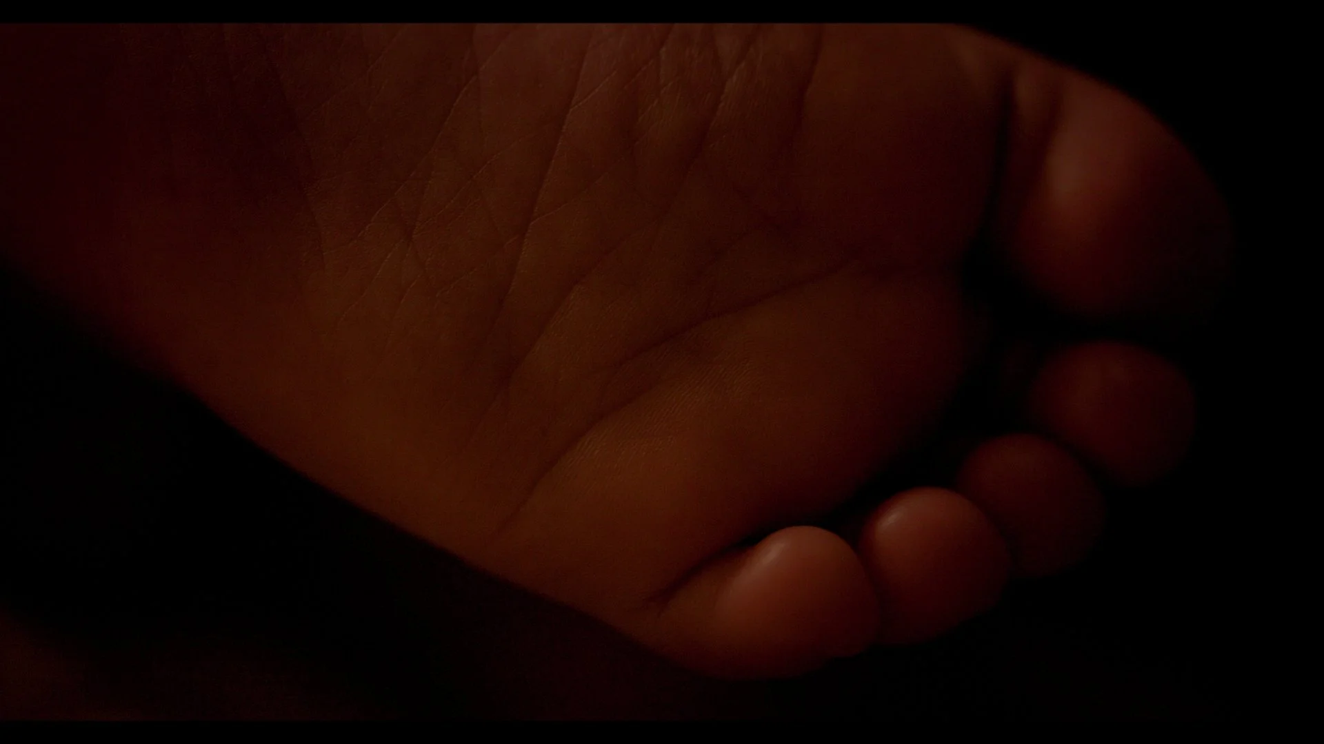 Close-up of a person's hand resting on a dark surface.