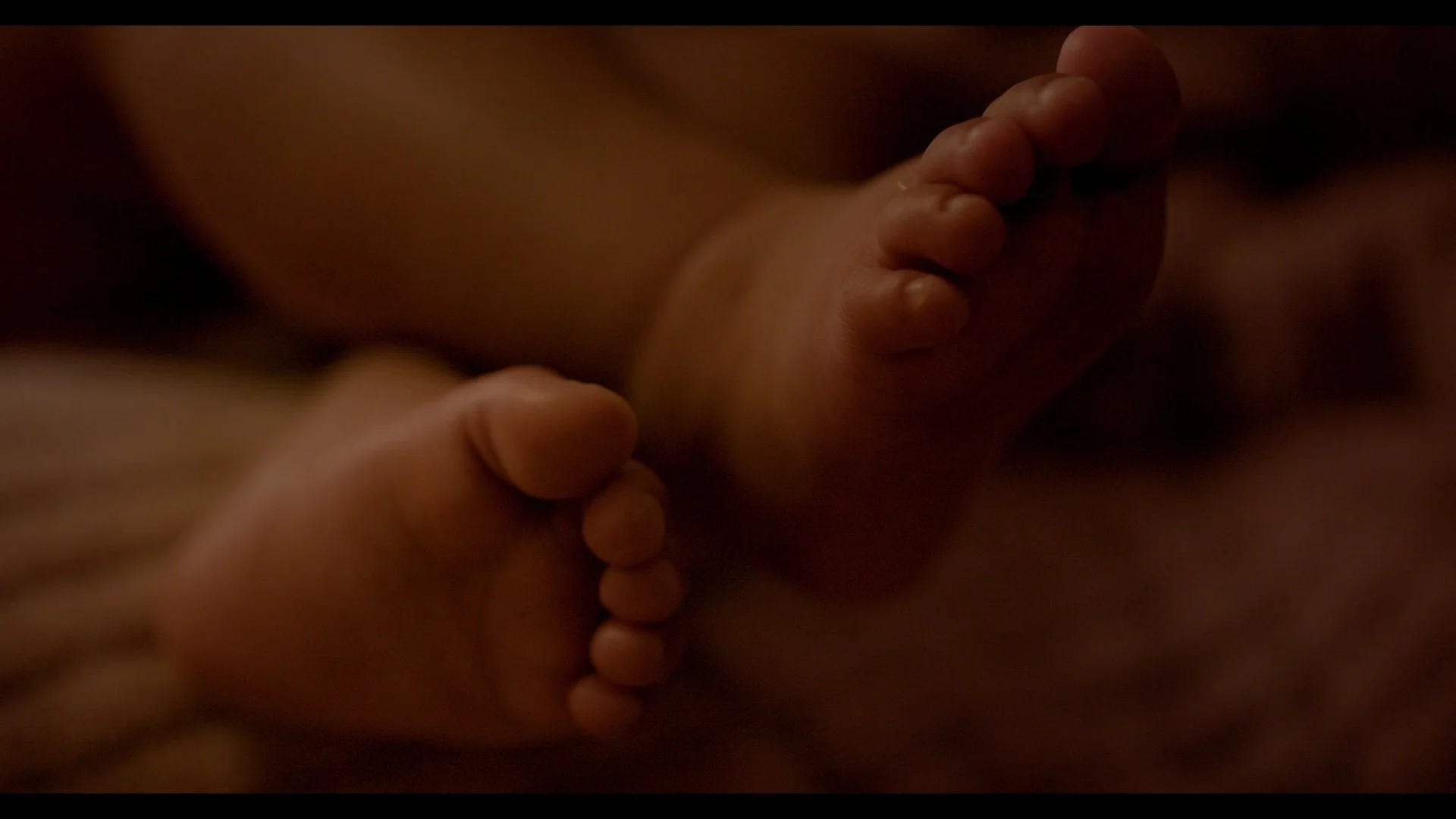 Close-up of a person's hand holding a tiny baby foot.